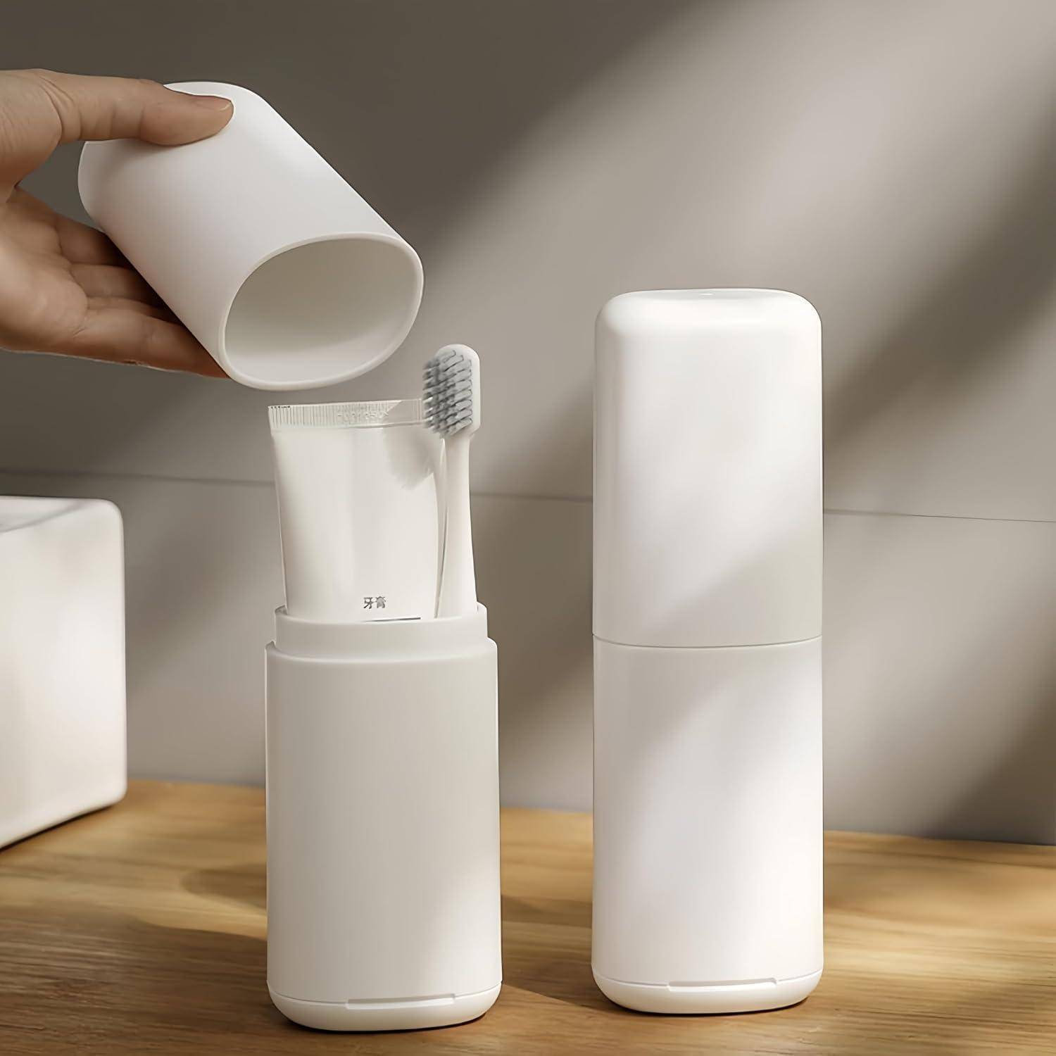 Hand platziert eine weiße Tasse neben einem Zahnbürstenhalter im Badezimmer mit Zahnpasta und Zahnbürste, neben einem passenden weißen Reisebehälter auf einer Holzoberfläche.