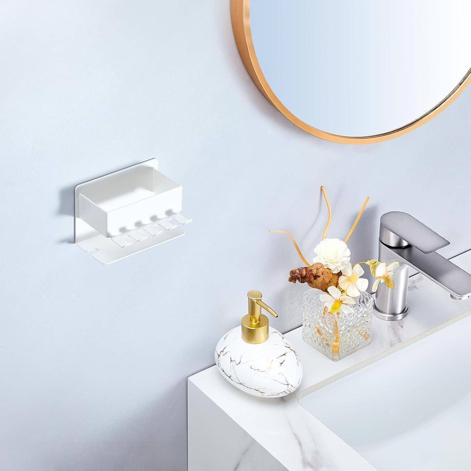 Modernes Badezimmerwaschtisch mit Chromarmatur, Marmor-Seifenspender, Blumendekoration und wandmontiertem Seifenhalter neben einem runden Spiegel.