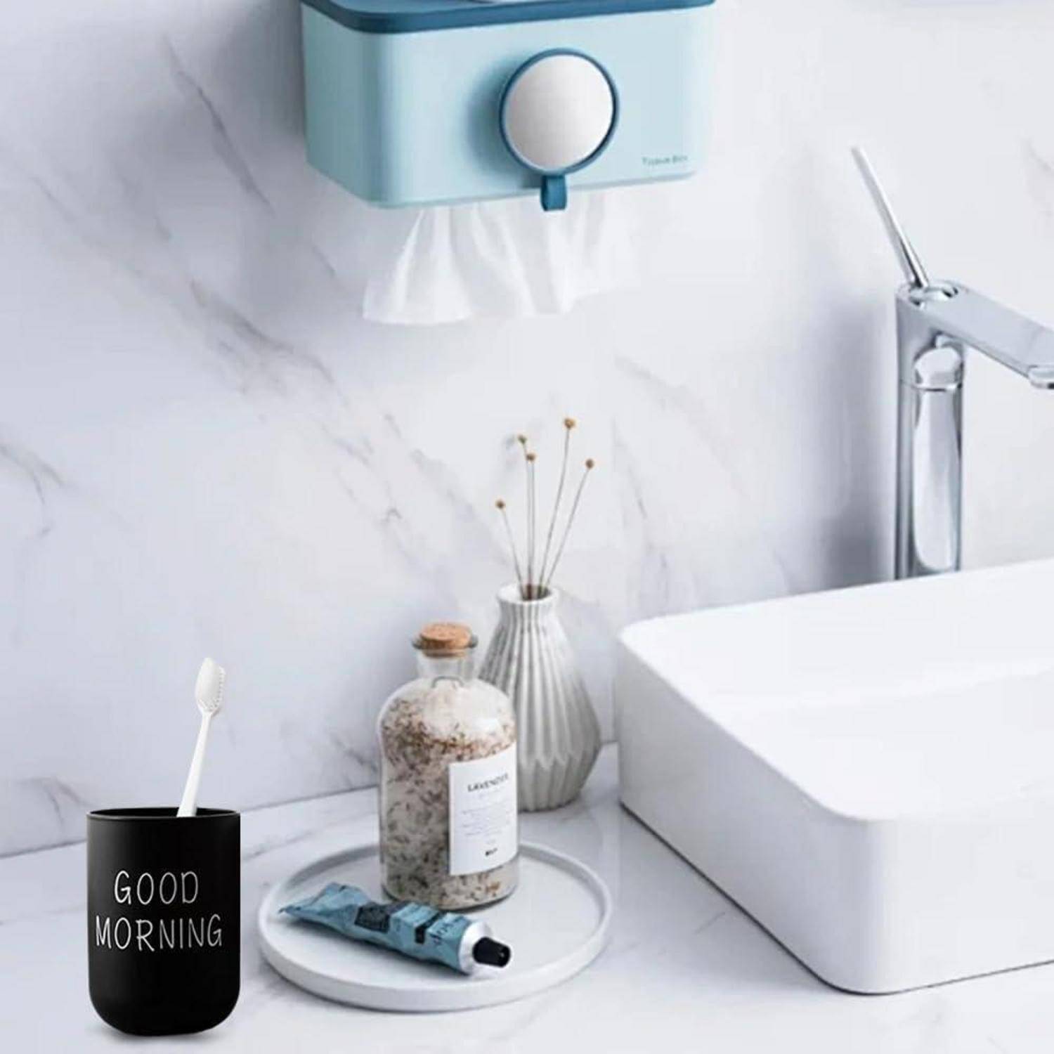 Moderner Badezimmer-Waschtisch mit schwarzer 'GUTEN MORGEN' Tasse und Zahnbürste, Seifenflasche, Vase, Handtuchspender und Wasserhahn.