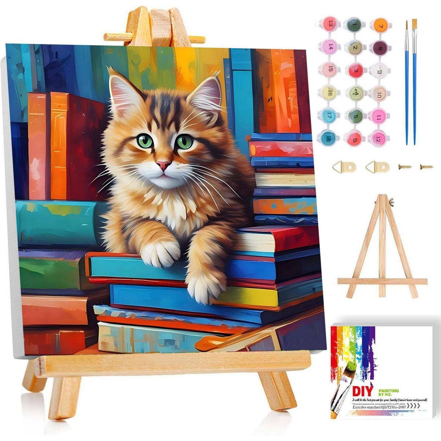 DIY-Malset-Bild, das eine bemalte Katze zeigt, die auf gestapelten farbigen Büchern auf einer kleinen Holzstaffelei sitzt, mit Farbtöpfen, Pinseln und Werkzeugen im Lieferumfang.