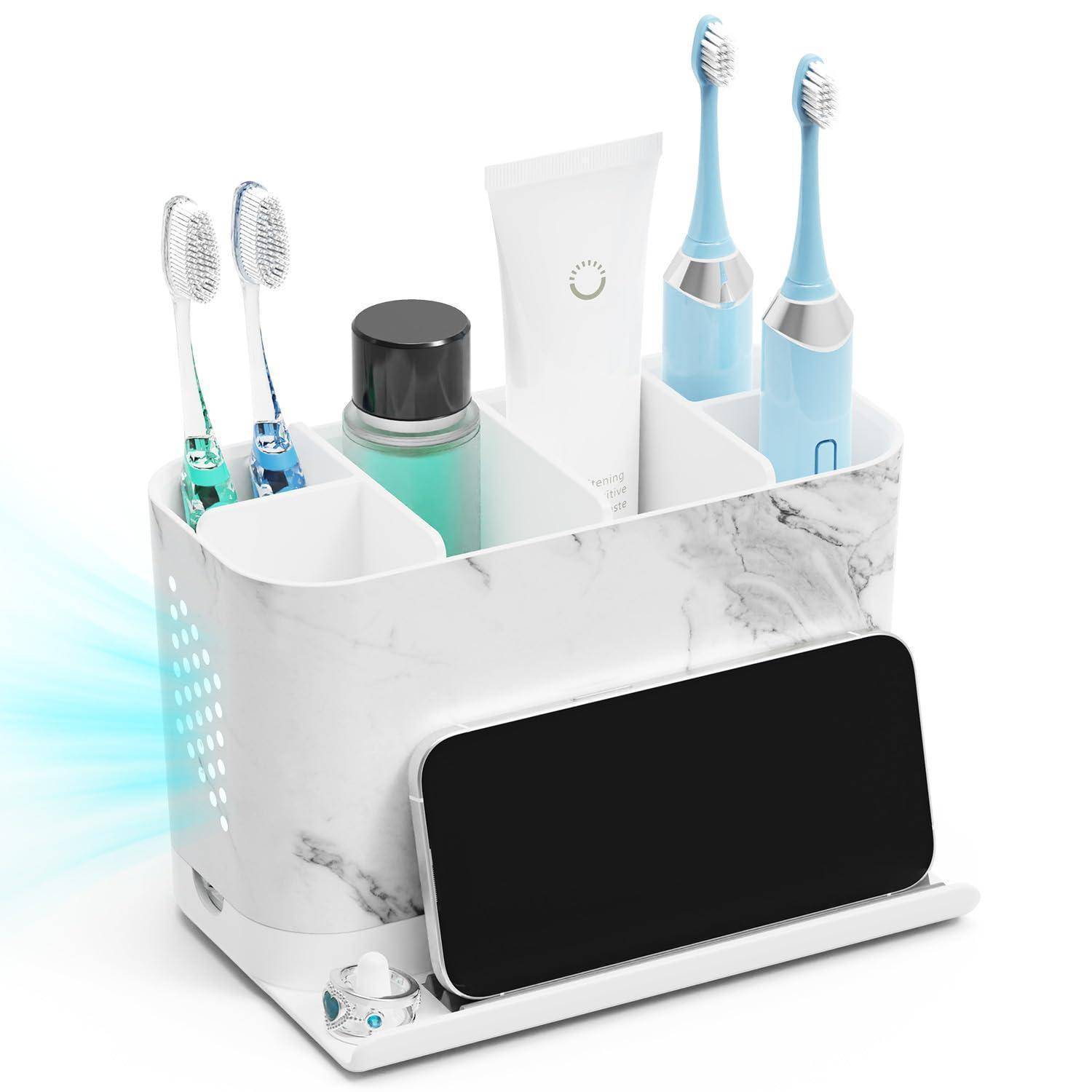 Badezimmer-Organizer mit Marmormuster, der elektrische Zahnbürsten, manuelle Zahnbürsten, Zahnpasta und ein Glas hält, mit einer vorne angebrachten Smartphone-Ladestation.