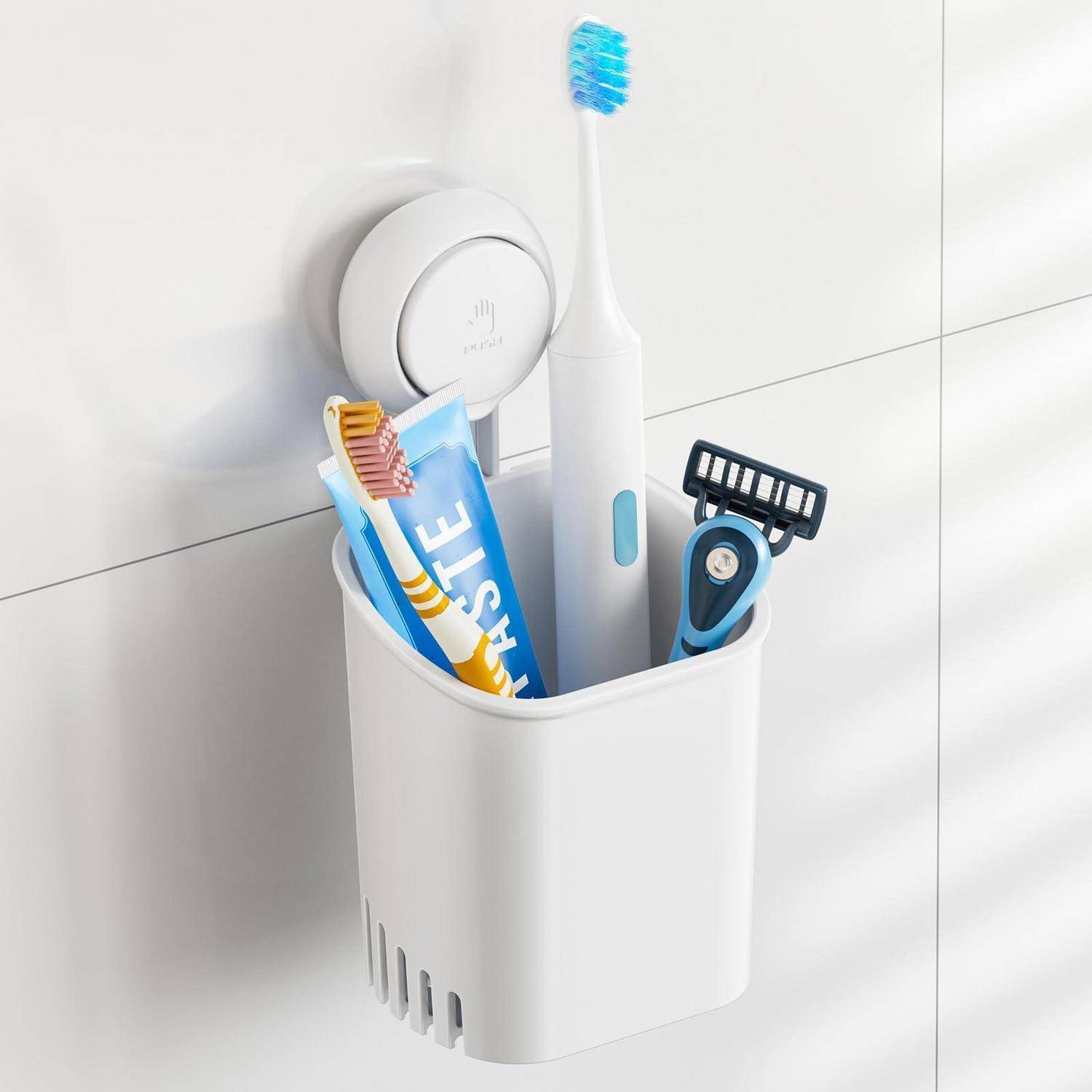 An der Wand montierter Badezimmerhalter, der eine elektrische Zahnbürste, Zahnpasta, manuelle Zahnbürsten und einen Rasierer auf einer weißen gekachelten Wand enthält.