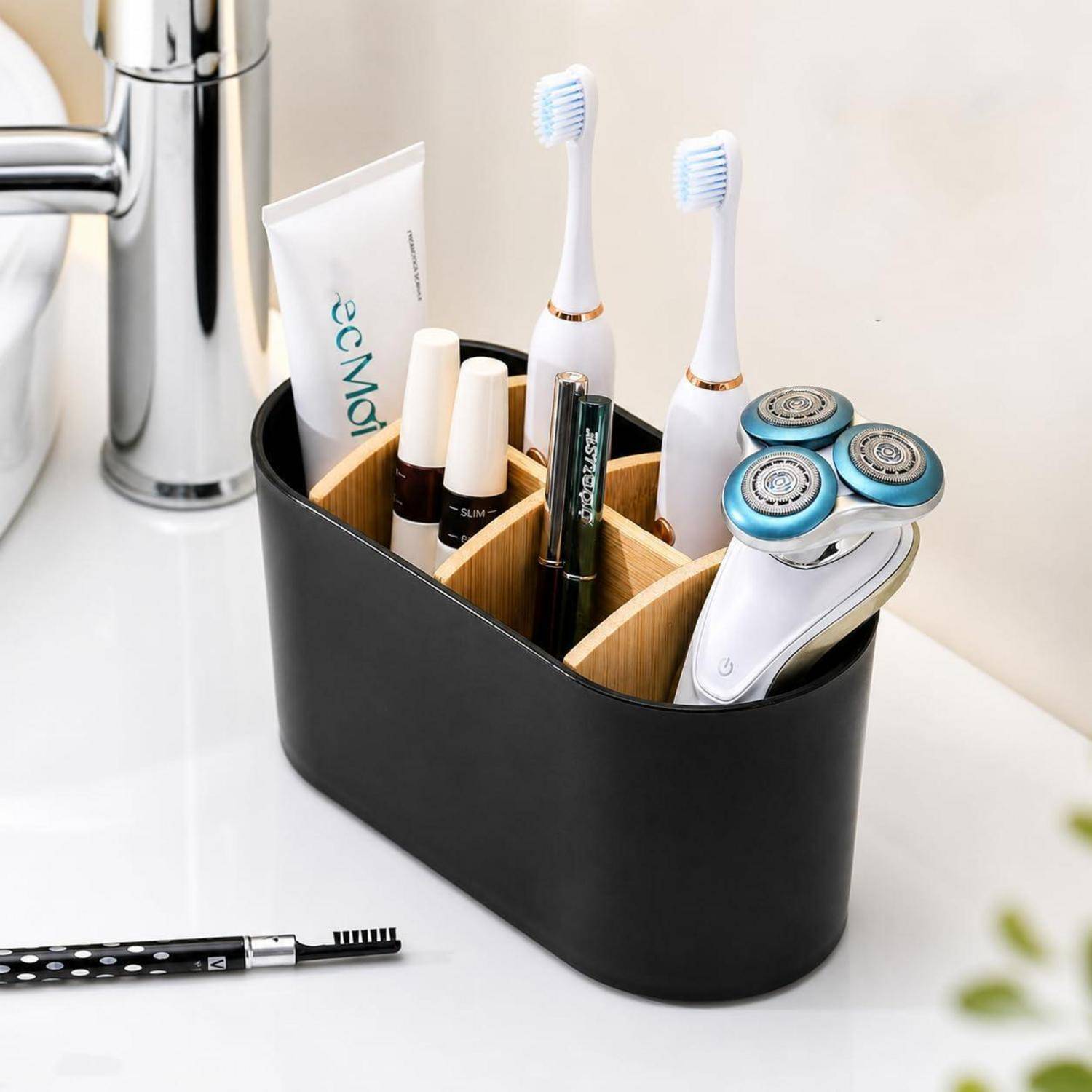 Badezimmer-Arbeitsplatte-Organizer mit zwei elektrischen Zahnbürsten, Rasierer, Zahnpasta und Make-up-Artikeln neben einem Waschbecken.