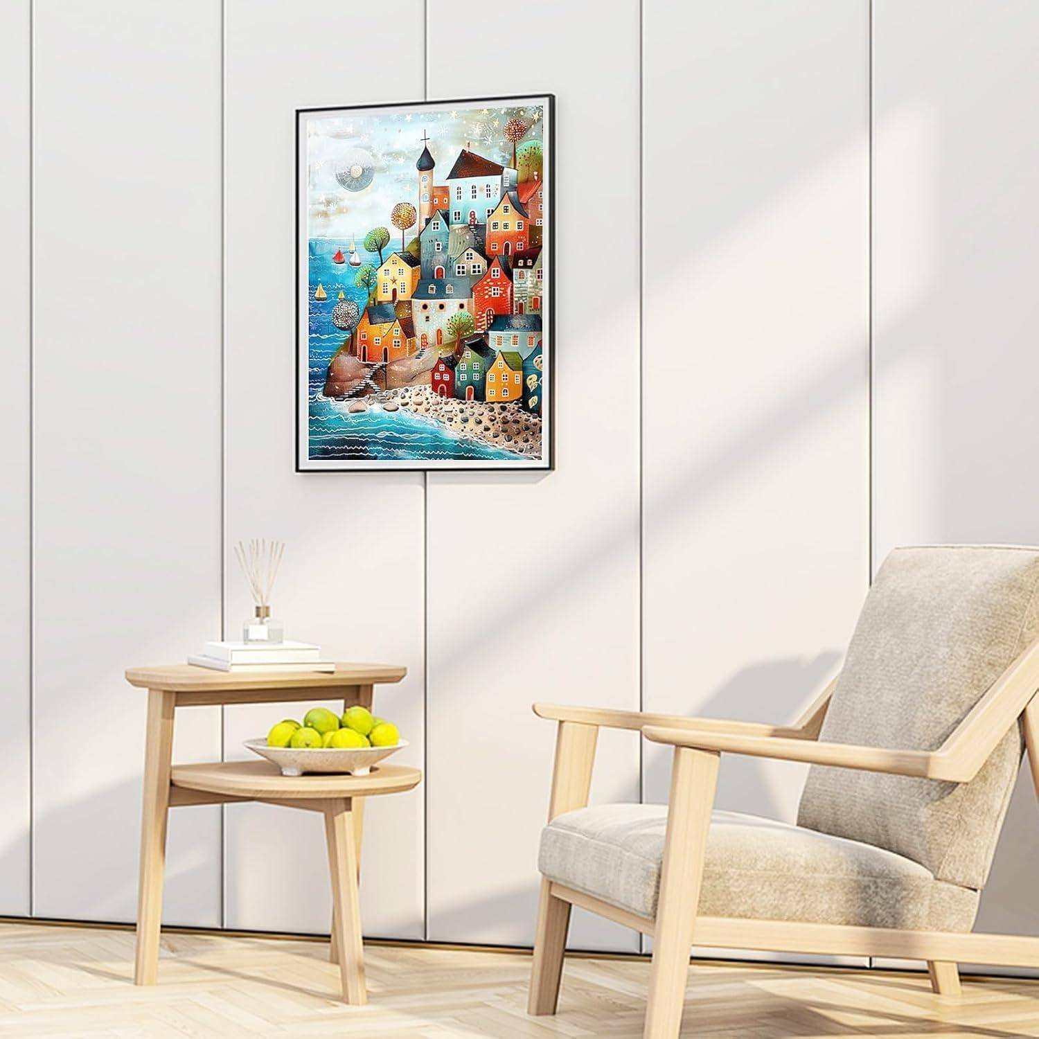 Modernes Wohnzimmer mit einem beigefarbenen Sessel, kleinem Holzbeistelltisch mit grünen Äpfeln und farbenfrohem Gemälde eines Küstendorfes an einer weiß vertäfelten Wand.