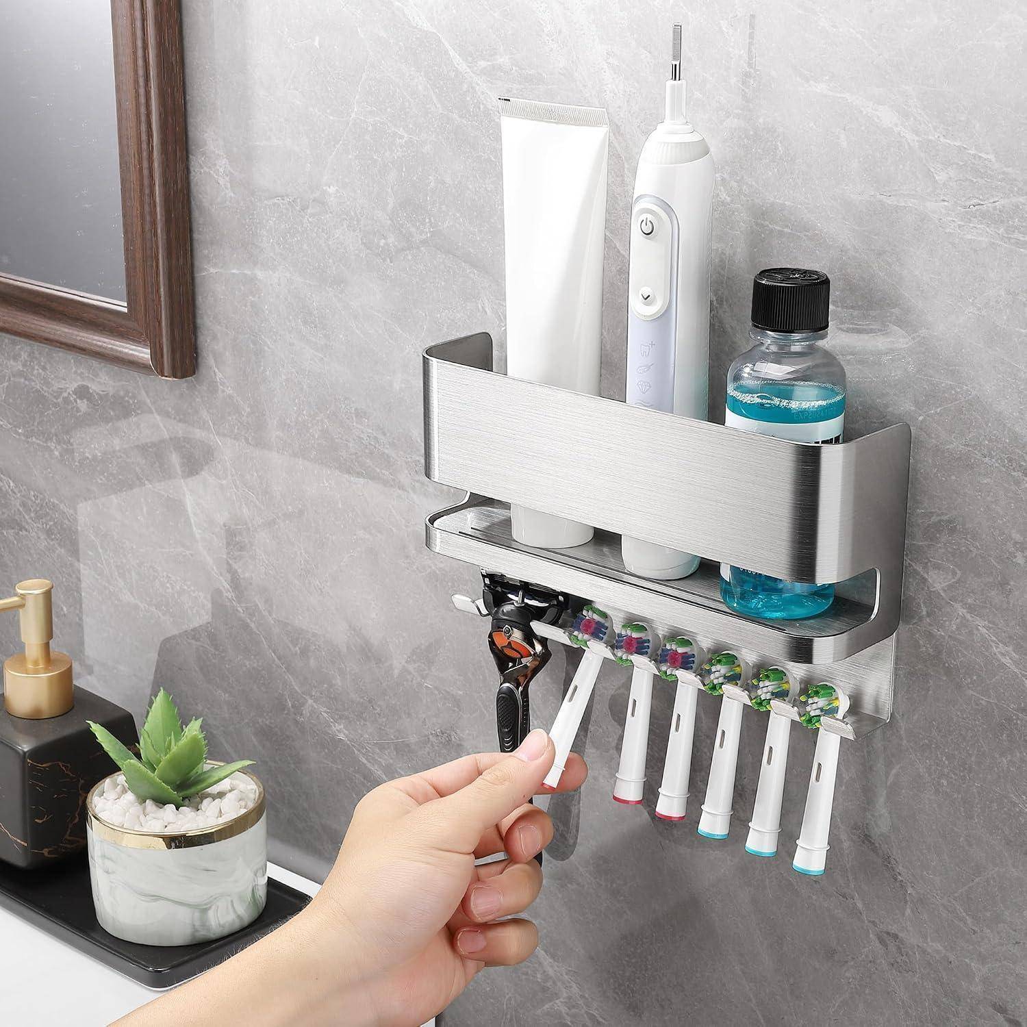 Badezimmer-Wandorganizer, der Zahnbürsten, eine elektrische Zahnbürste, Zahnpasta und Mundwasser hält, mit einer Hand, die eine Zahnbürste entnimmt.