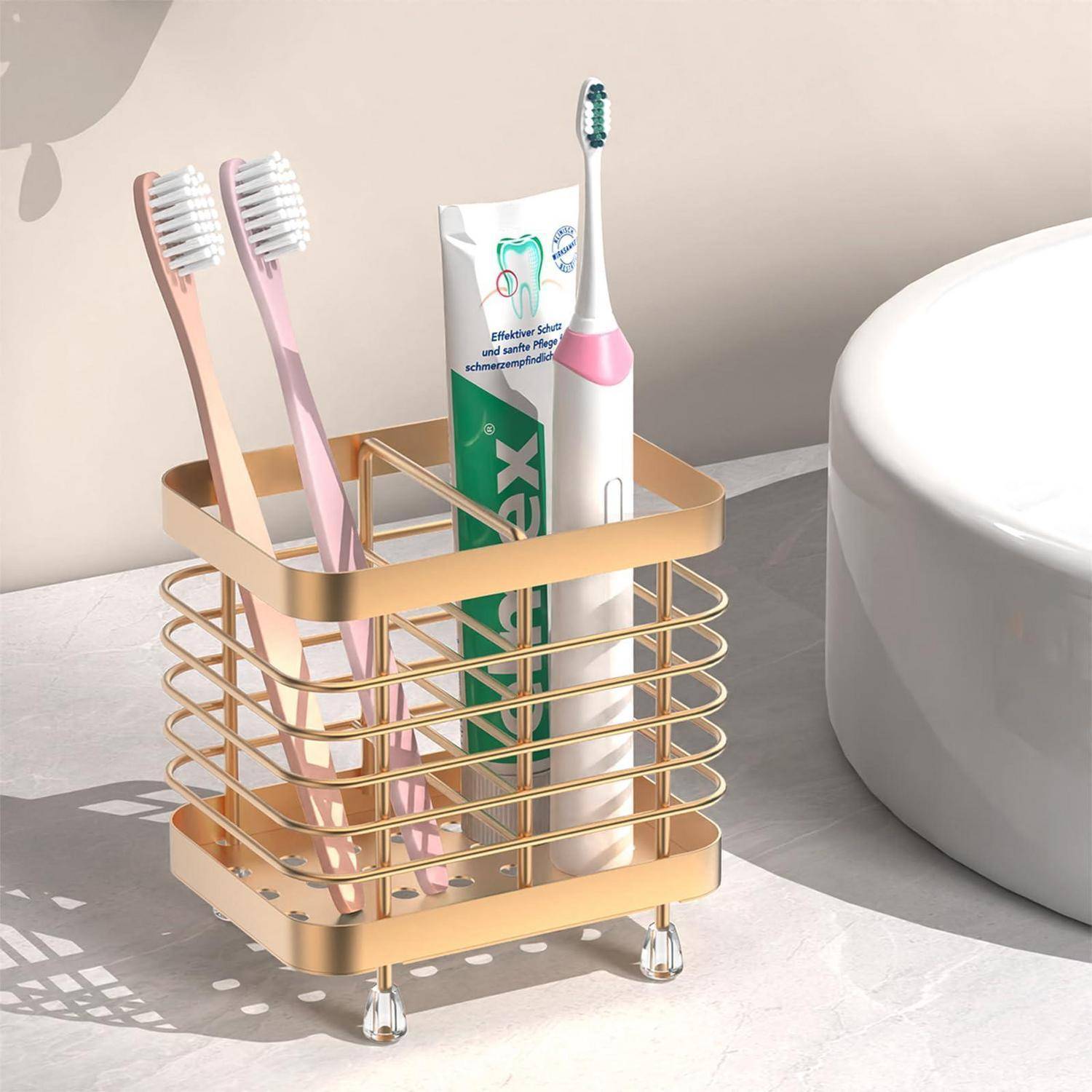 Goldenes Badezimmerregal mit zwei Zahnbürsten, einer Zahnpastatube und einer elektrischen Zahnbürste neben einem Waschbecken.