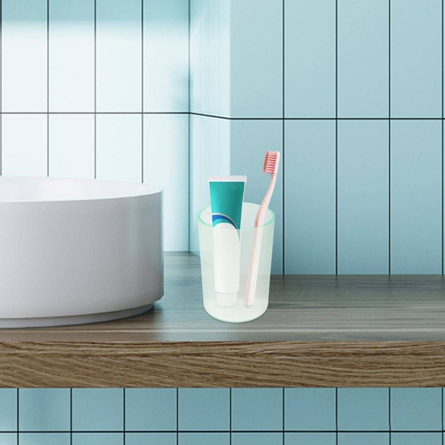Zahnbürste und Zahnpasta in einem durchsichtigen Behälter auf einer Badezimmerablagefläche neben einem Waschbecken.