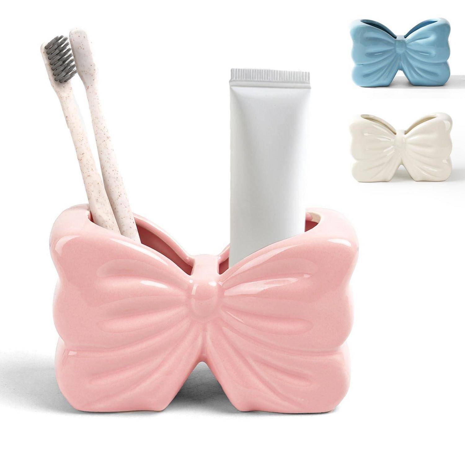 Schmetterlingsförmiger Keramik-Badezimmerorganizer zum Halten von Zahnbürsten und einer Zahnpastatube, gezeigt in Pink mit Blau- und Cremeoptionen.