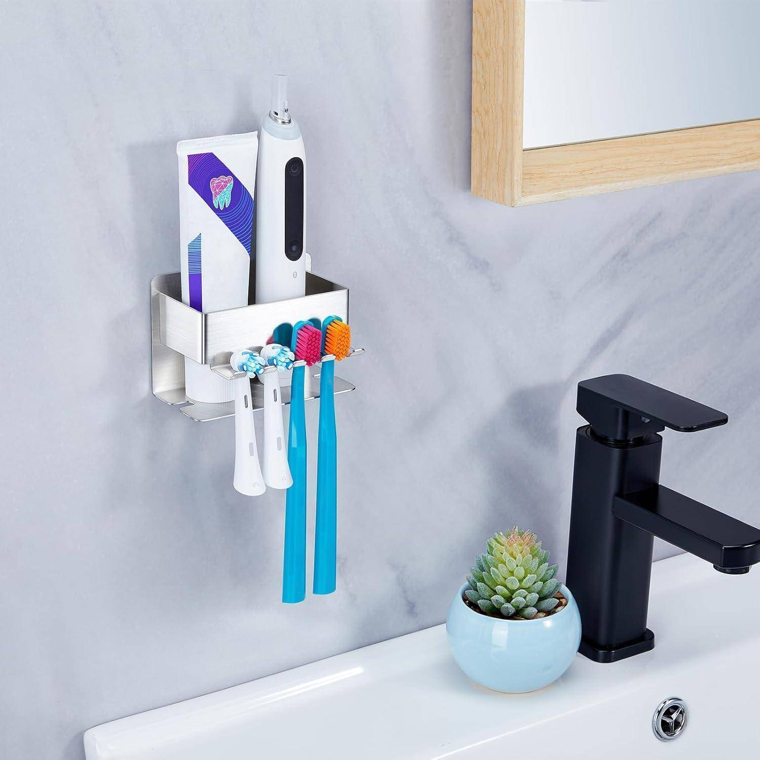 Wandmontierter Badezimmer-Organizer, der eine elektrische Zahnbürste, Zahnpasta und mehrere manuelle Zahnbürsten neben einem Wasserhahn und einer kleinen Topfpflanze hält.
