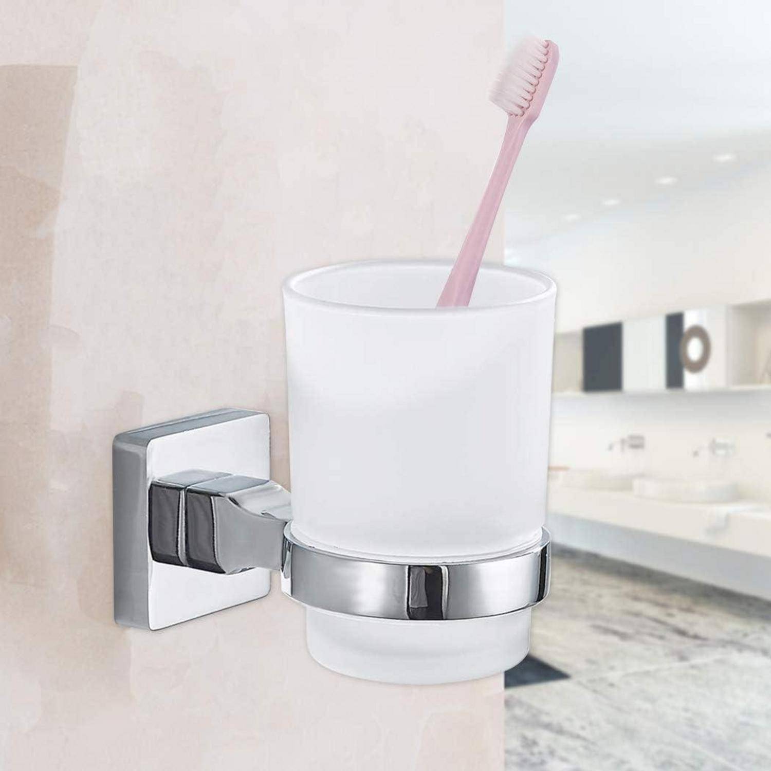 Zahnbürstenbecher-Halter an einer Badezimmerwand montiert, der einen mattglasigen Becher mit einer rosa Zahnbürste hält.