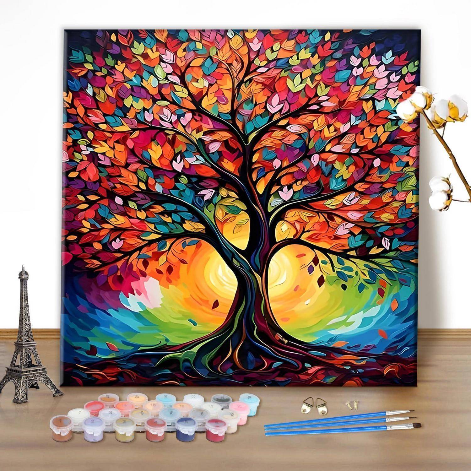Buntes Leinwandgemälde eines Baumes mit mehrfarbigen Blättern und Wurzeln, dargestellt mit Farbdosen und Pinseln auf einem Tisch, was auf ein Kunstprojekt hindeutet.