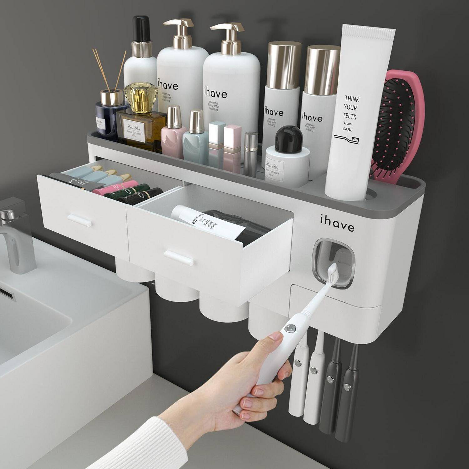 Wandmontierter Badezimmerorganizer mit Toilettenartikeln, Schubladen und Zahnbürsten; eine Hand benutzt eine elektrische Zahnbürste in der integrierten Halterung.