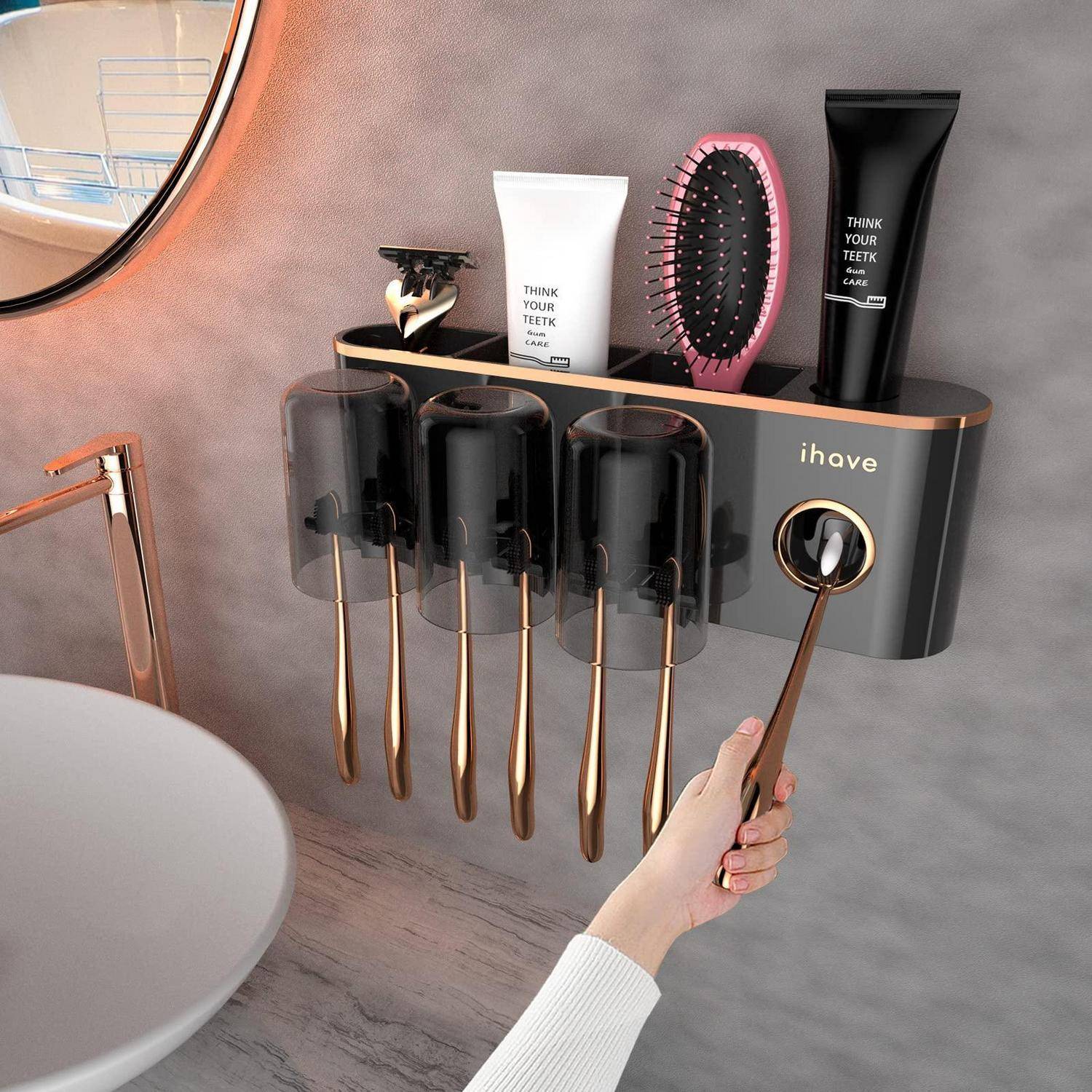 An der Wand montierter Badezimmerorganizer mit Zahnbürsten, Zahnpasta und einer Haarbürste, mit einer Hand, die den angebrachten Becherspender verwendet.