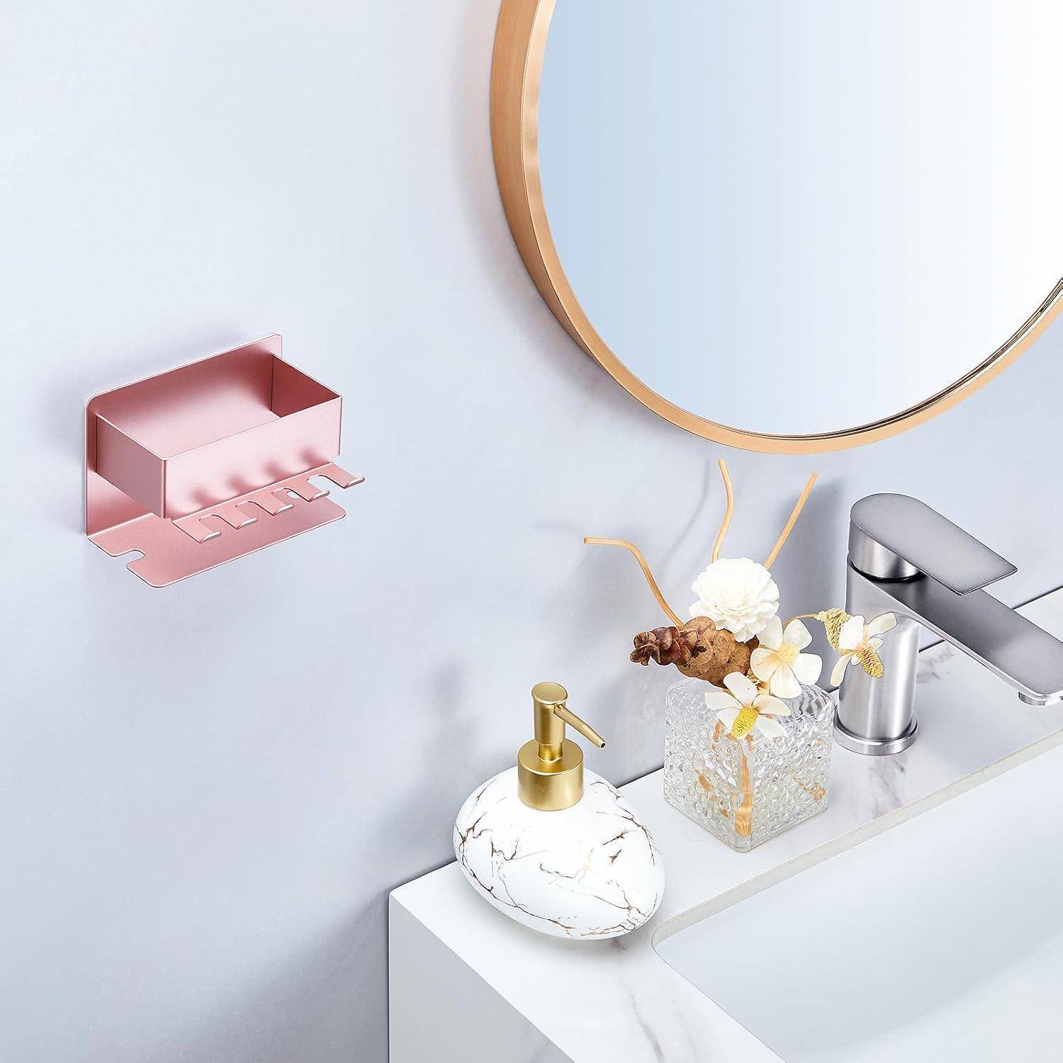 Badezimmerwaschbereich mit rundem Spiegel, modernem Wasserhahn, Seifenspender und kleiner Blumenvase; rosa wandmontierter Organizer hängt auf der linken Seite.