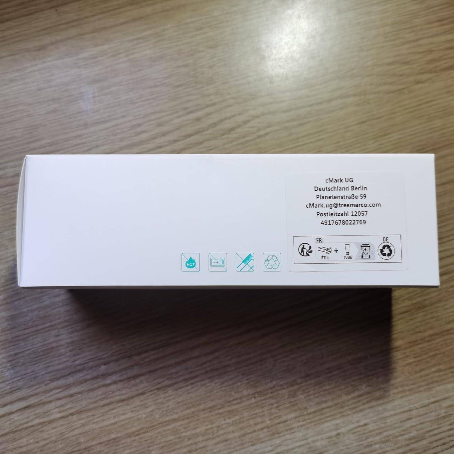 Weiße rechteckige Produktverpackung auf einem Holztisch, beschriftet mit cMark UG in Berlin mit E-Mail-Adresse, Postadresse und kleinen Handlings-/Recycling-Symbolen