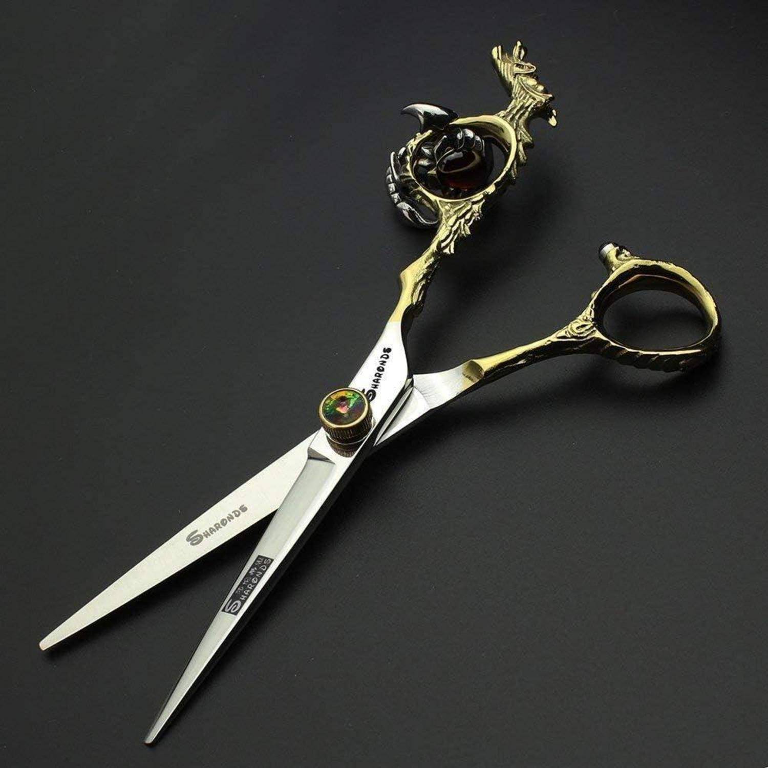 Dekorative gold-und-schwarze Frisierscheren mit verziertem Griff und einem zentralen Edelstein, geöffnet auf dunklem Hintergrund dargestellt.