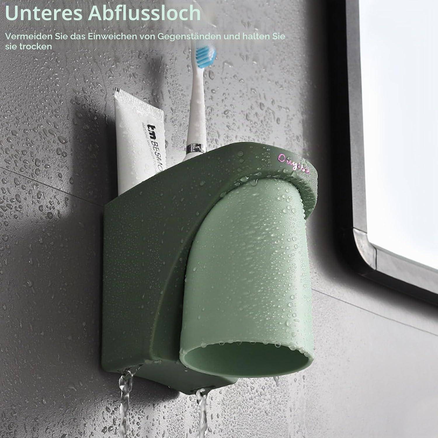 Grüner wandmontierter Zahnbürstenhalter für das Badezimmer mit Drainage, dargestellt mit Nässe und Wasser, das tropft; deutscher Text warnt vor „Unteres Abflussloch
