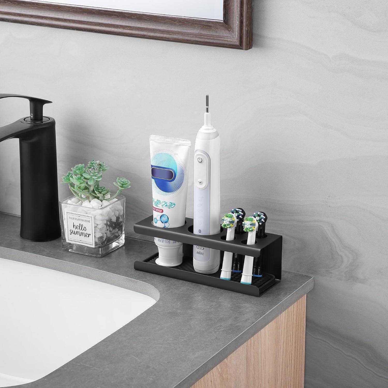 Badezimmer-Arbeitsplatte-Organizer hält eine elektrische Zahnbürste, Zahnpasta und einen angetriebenen Zahnbürstengriff neben einem Waschbecken und einem Wasserhahn.