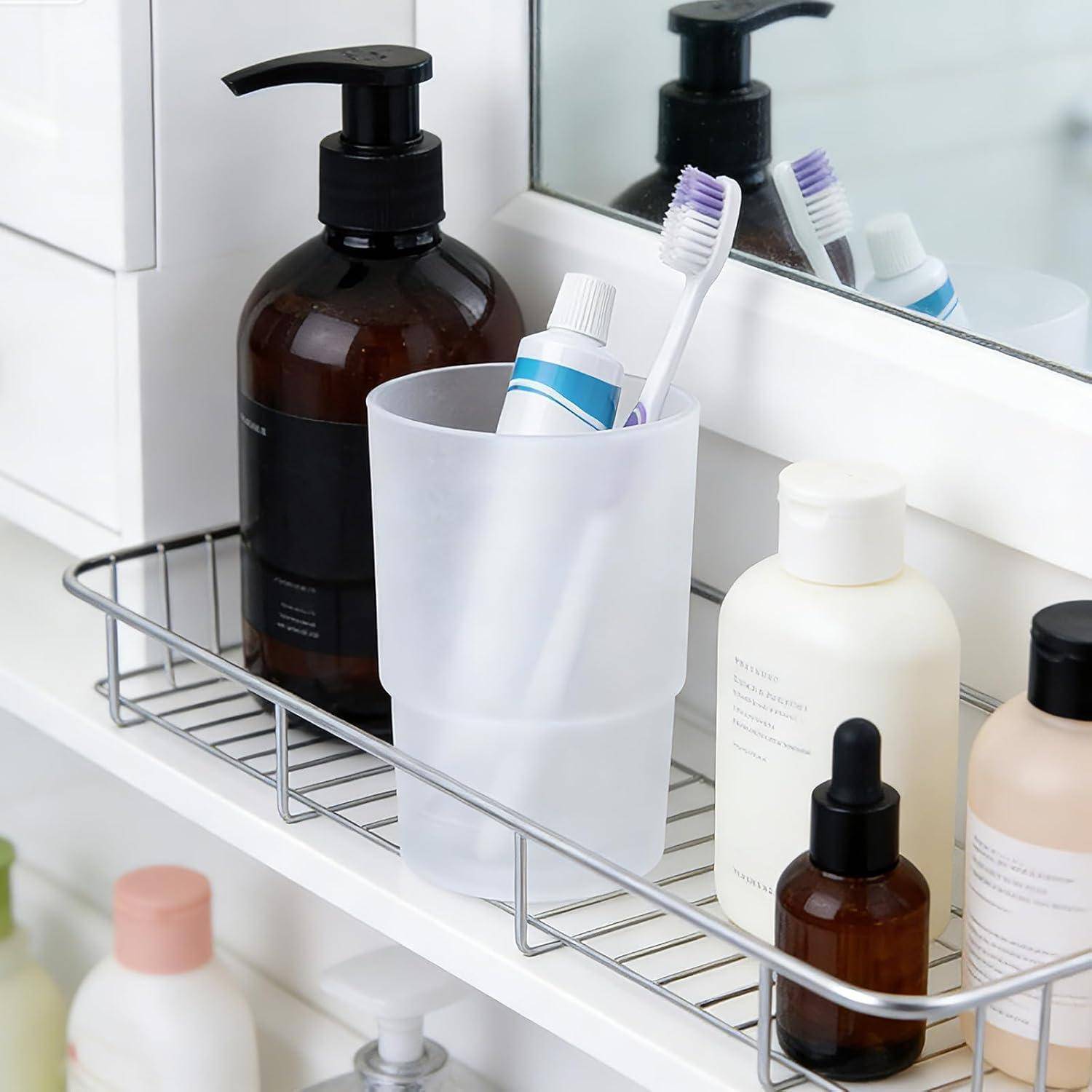 Badezimmer-Waschtischablage mit einem mattiertem Becher, der Zahnbürsten und Zahnpasta hält, umgeben von Seife und Hautpflegeflaschen