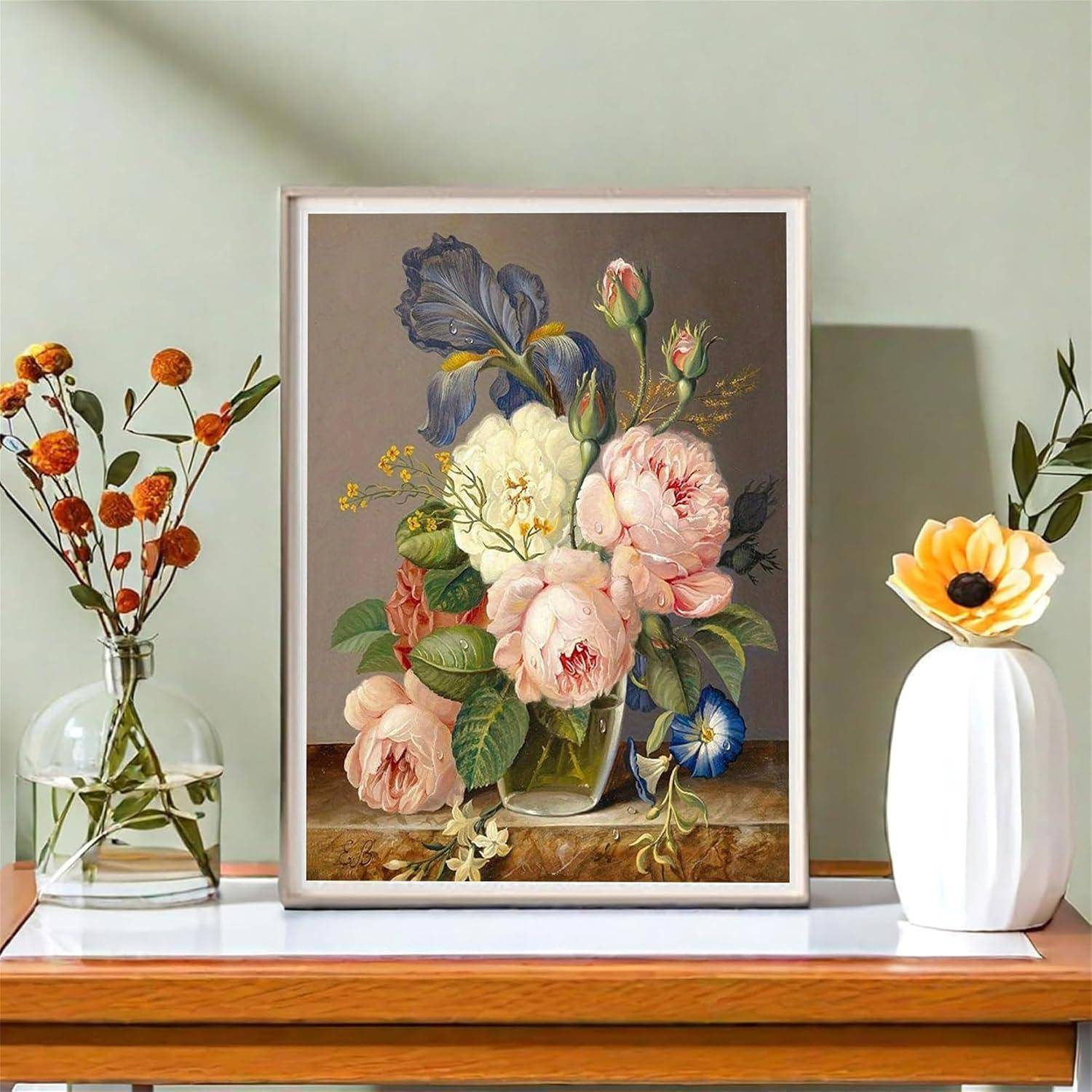 Ein gerahmtes Blumengemälde ist auf einem Regal zentriert, flankiert von einer kleinen Glasvase mit orangefarbenen Blumen und einer weißen Vase mit einer gelben Blume.