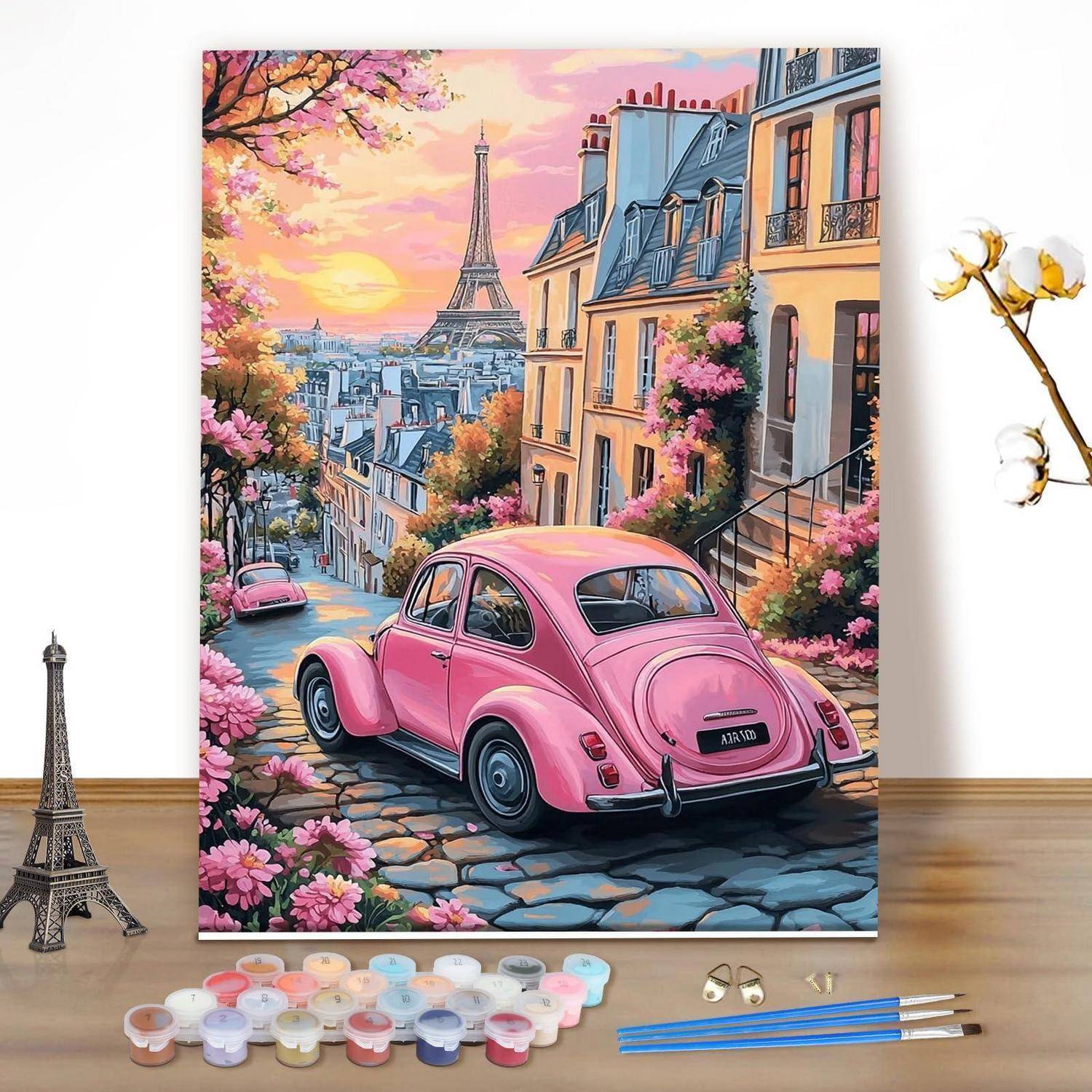 Ein rosa Vintage-Auto auf einer Pariser Straße mit dem Eiffelturm bei Sonnenuntergang, umgeben von Blumen; dargestellt als Malen-nach-Zahlen-Leinwand mit Farben und Pinseln.