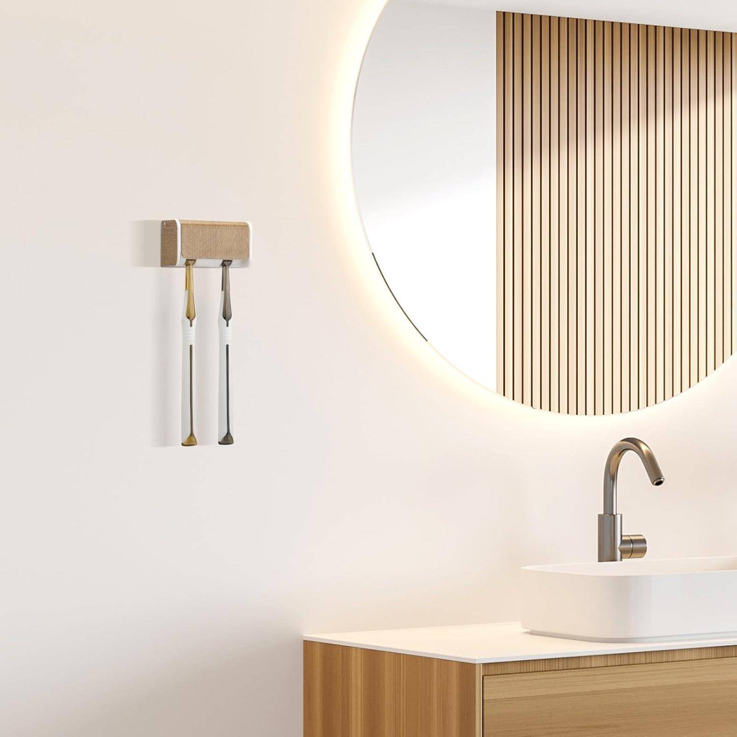 Minimalistische Badezimmerkonsole mit rundem beleuchteten Spiegel, wandmontiertem Wasserhahn und Holzschrank neben einem Handtuchhalter an einer weißen Wand.
