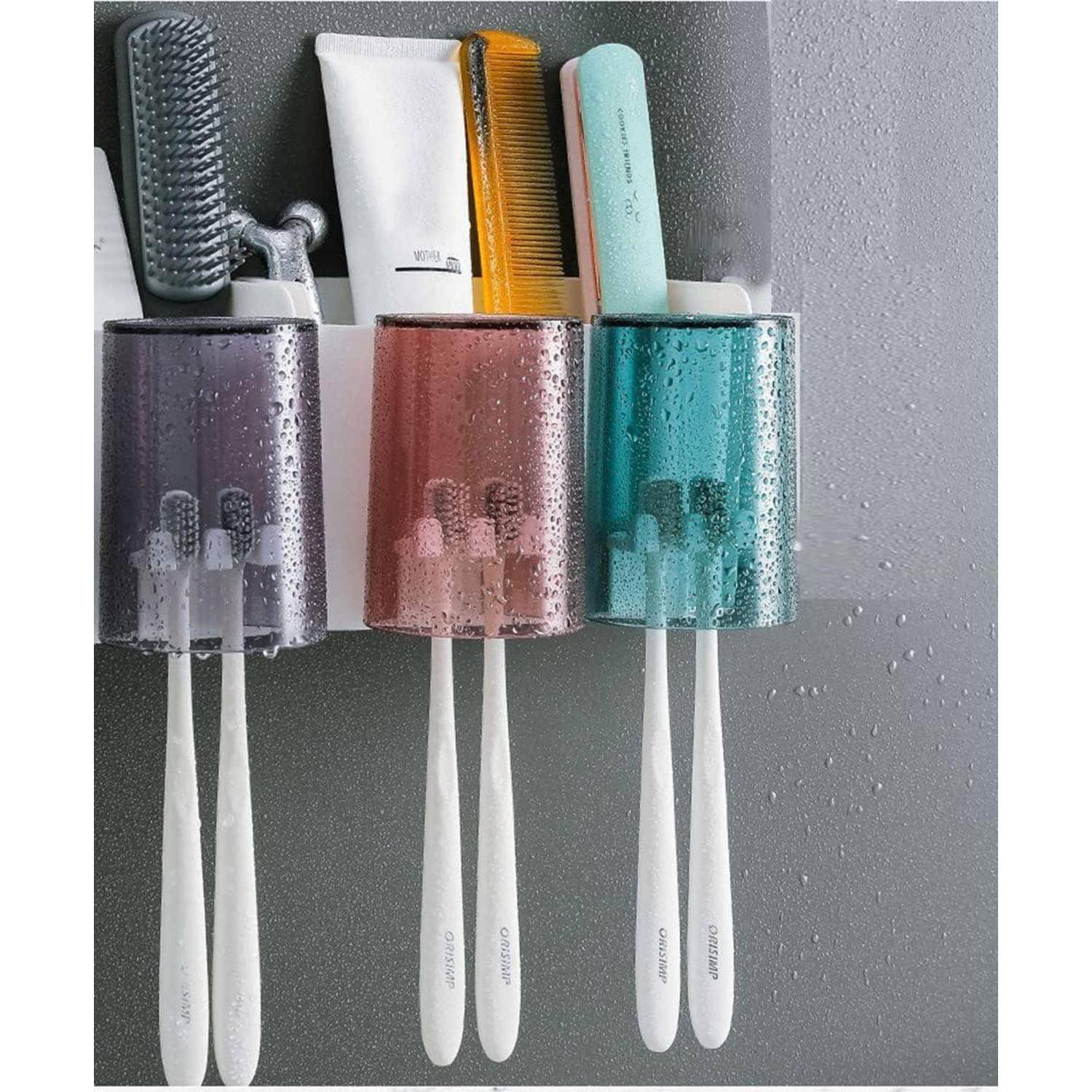 Drei wandmontierte Halter organisieren Zahnbürsten, einen Kamm und eine Tube Zahnpasta auf einer grauen Badezimmeroberfläche.