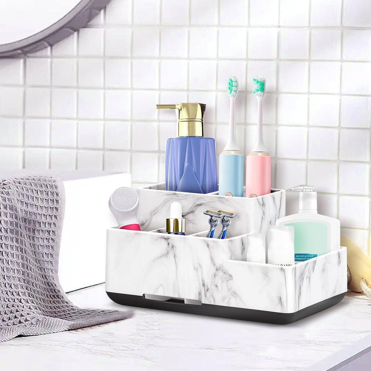 Marmorierter Badezimmer-Organizer mit Toilettenartikeln, einschließlich eines Seifenspenders, elektrischer Zahnbürsten, Rasierer und Hautpflegeflaschen auf einer Arbeitsplatte.