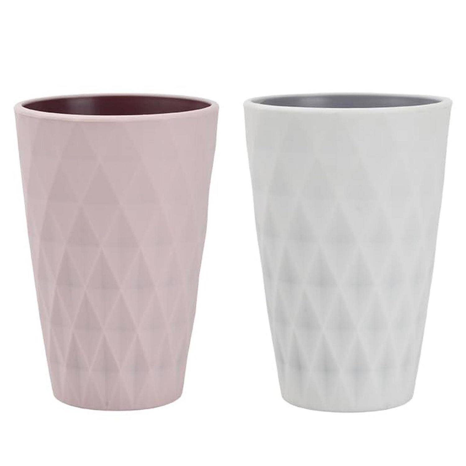 Zwei strukturierte, konisch zulaufende Becher oder Trinkgläser, einer rosa und einer weiß, nebeneinander auf einfachem Hintergrund gezeigt.