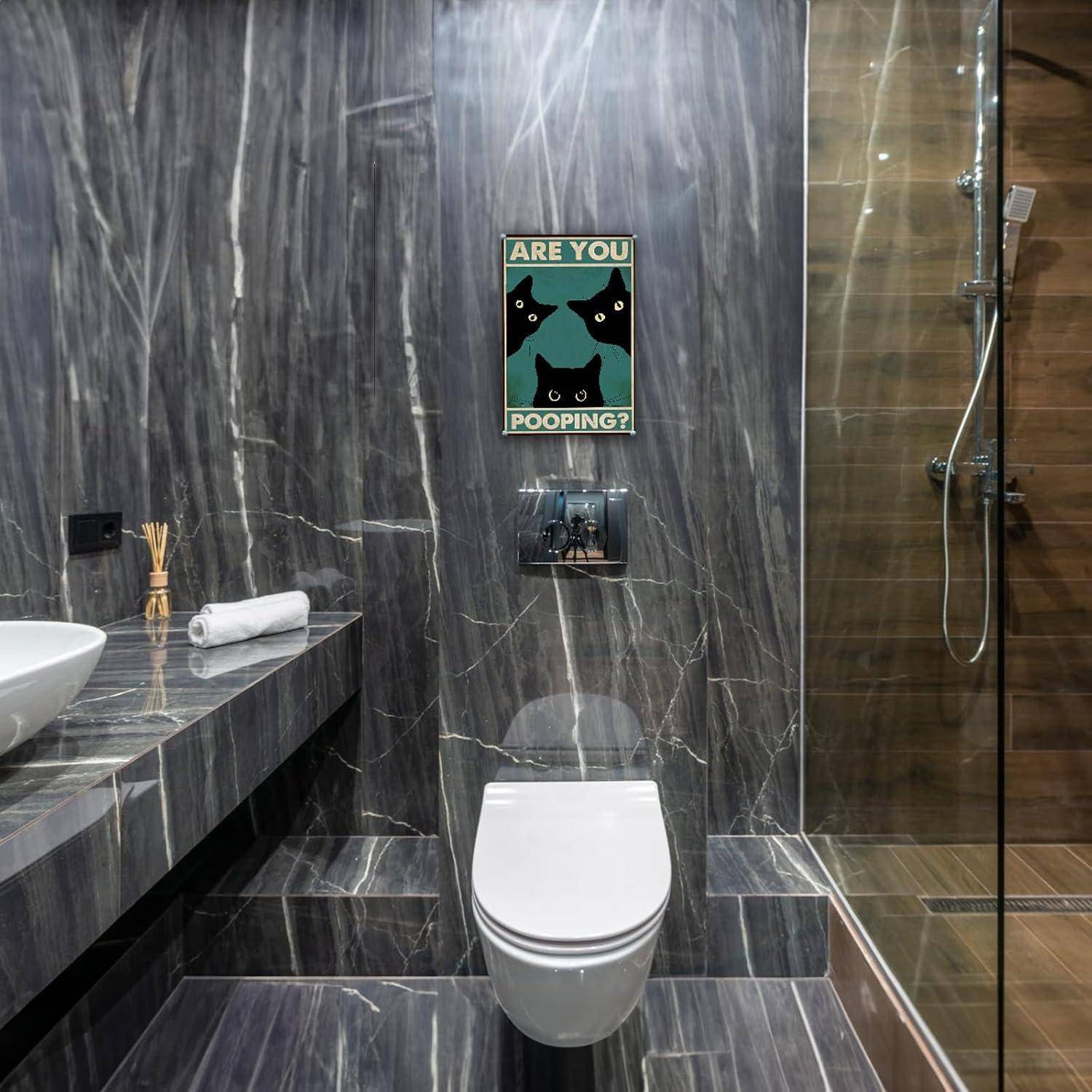 Modernes Badezimmer mit an der Wand montierter Toilette, Glasdusche und Waschbecken; ein humorvolles Wandschild über der Toilette liest 