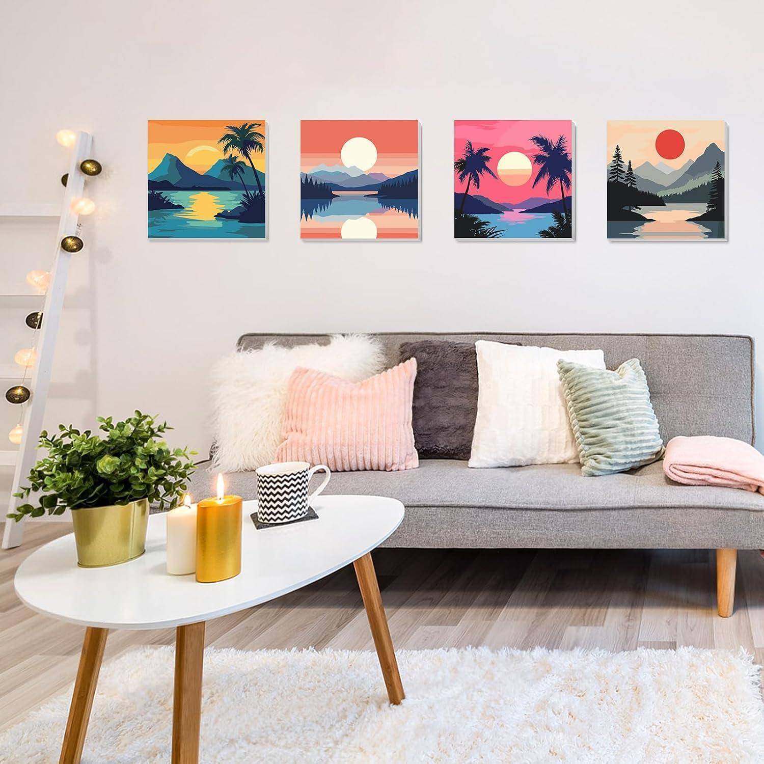 Gemütliches modernes Wohnzimmer mit grauem Sofa, weißem Couchtisch, Pflanze und Kerzen sowie vier farbenfrohen Sonnenuntergang-Landschaftsdrucken über dem Sofa.