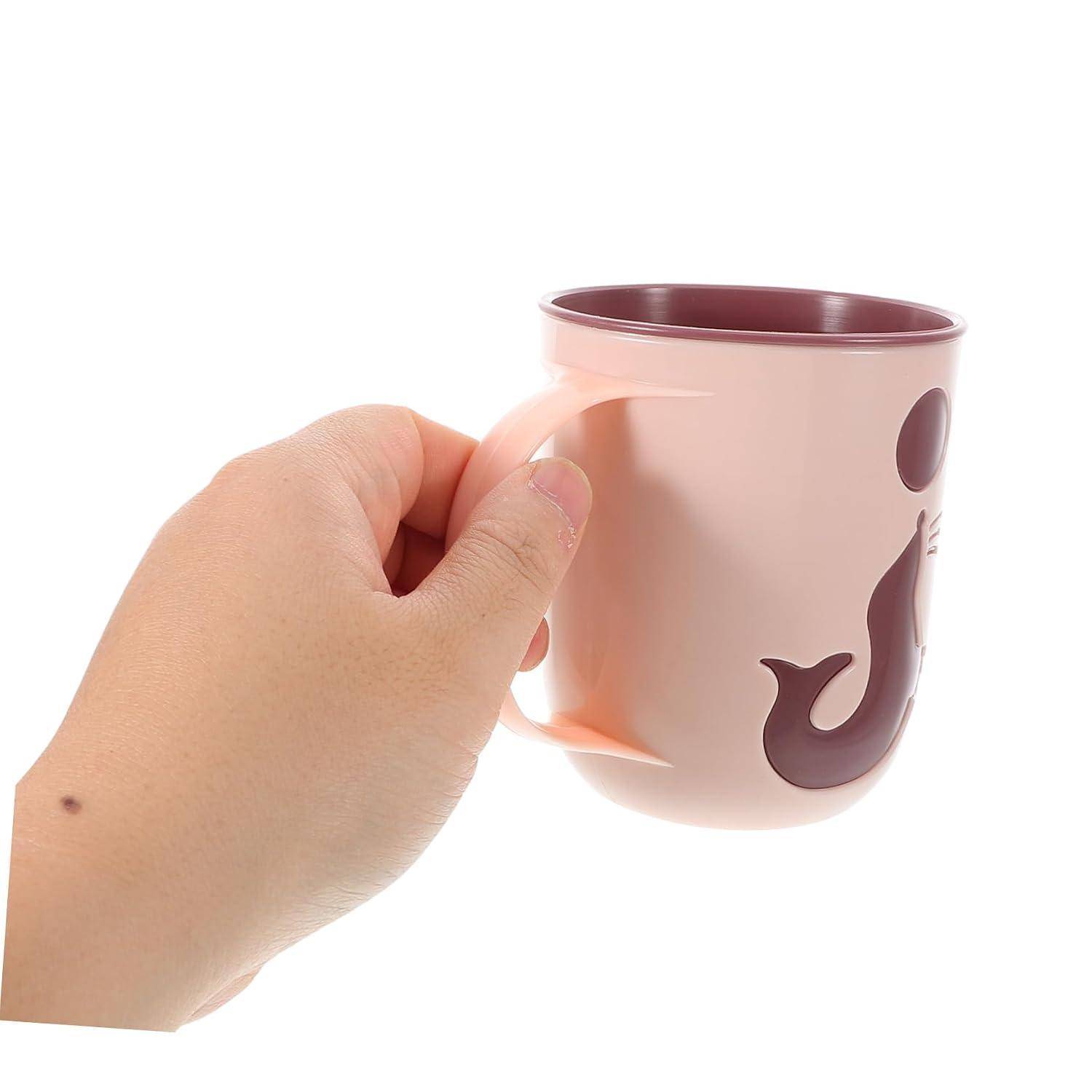 Eine Hand hält eine rosa Tasse mit dunklem Bordeauxrot im Inneren und Fischdesign auf weißem Hintergrund.