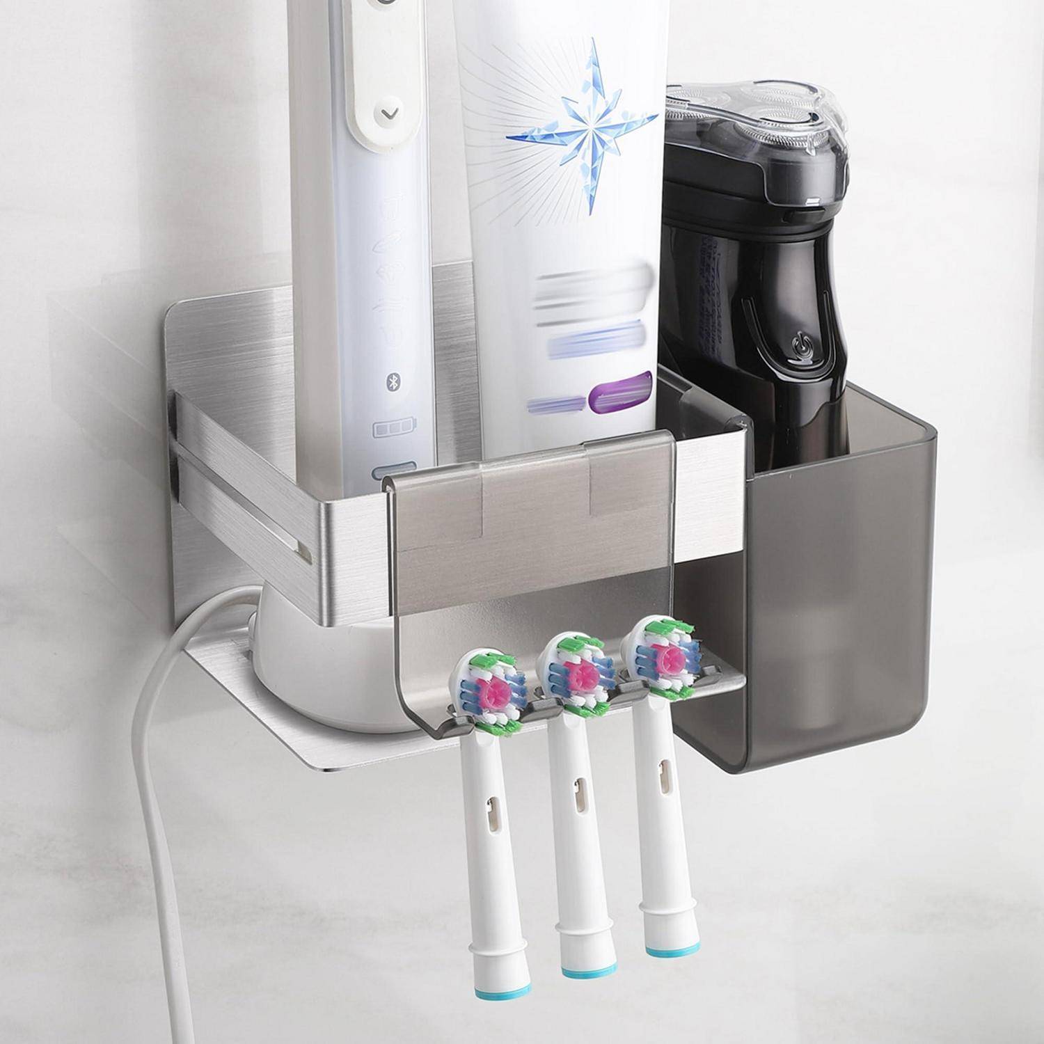 Wandmontierter Organizer mit einer elektrischen Zahnbürste, Zahnpasta und einem schwarzen Spender, mit drei Zahnbürstenköpfen, die darunter hängen.