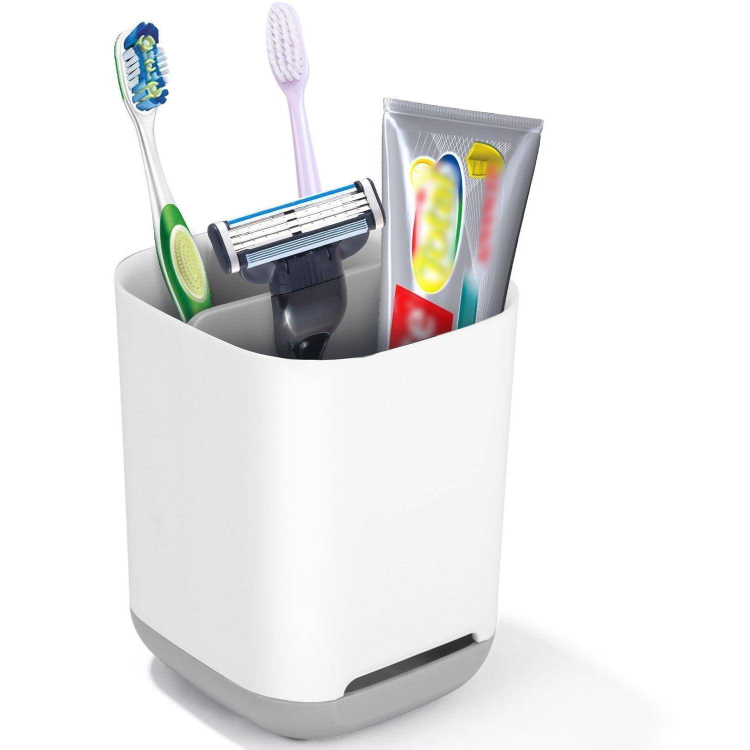 Zahnbürsten, Rasierer und Zahnpasta in einem Badezimmerorganizer auf weißem Hintergrund.