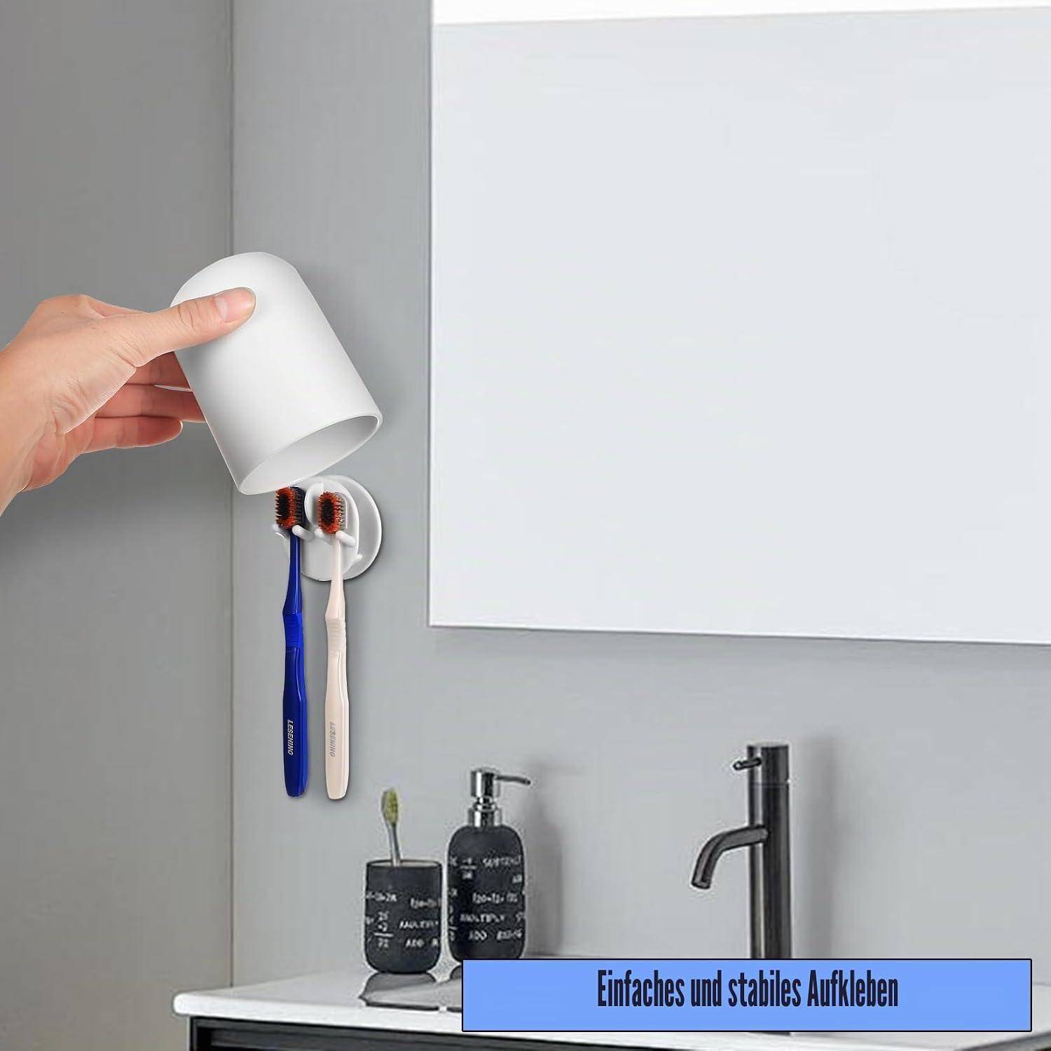 Hand platziert einen weißen Becher über einen wandmontierten Halter mit Zahnbürsten und Toilettenartikeln in der Nähe, was auf einen einfachen Badezimmer-Organizer mit Haftung hindeutet.