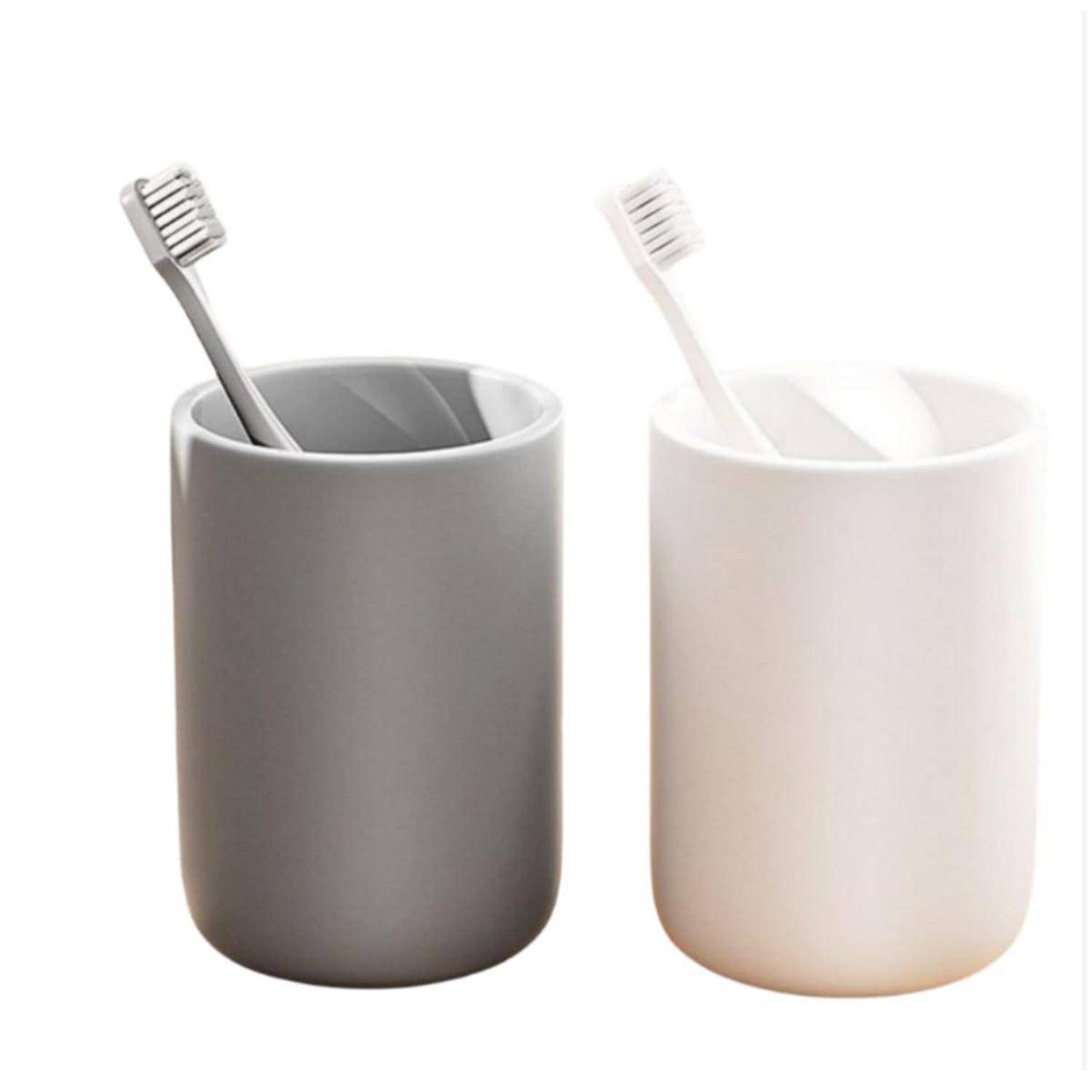 Zwei minimalistische Zahnbürstenhalter, einer grau und einer weiß, jeweils mit einer Zahnbürste auf weißem Hintergrund.