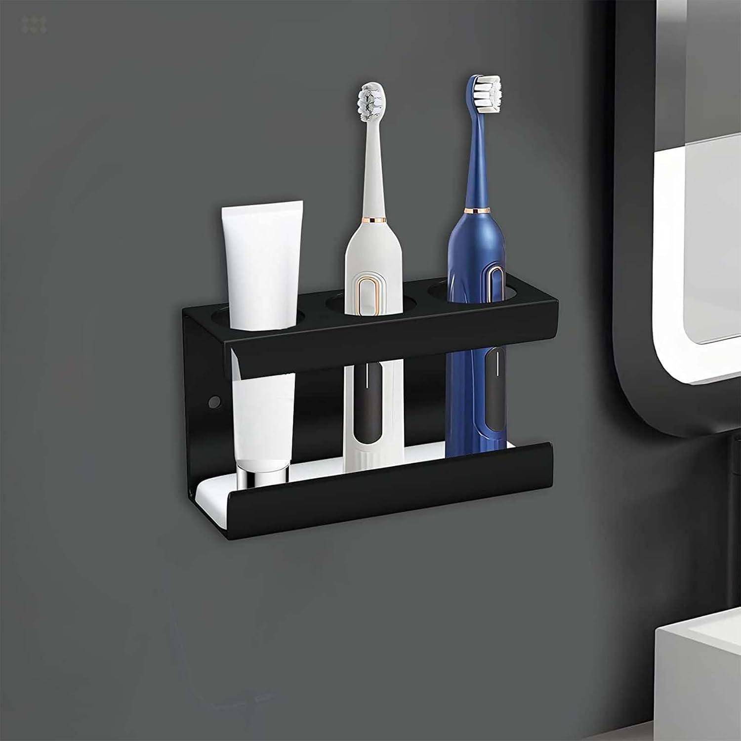 An der Wand montierter Badezimmer-Zahnbürstenhalter mit drei Zahnbürsten und einer Zahnpastatube auf einem dunklen Regal.