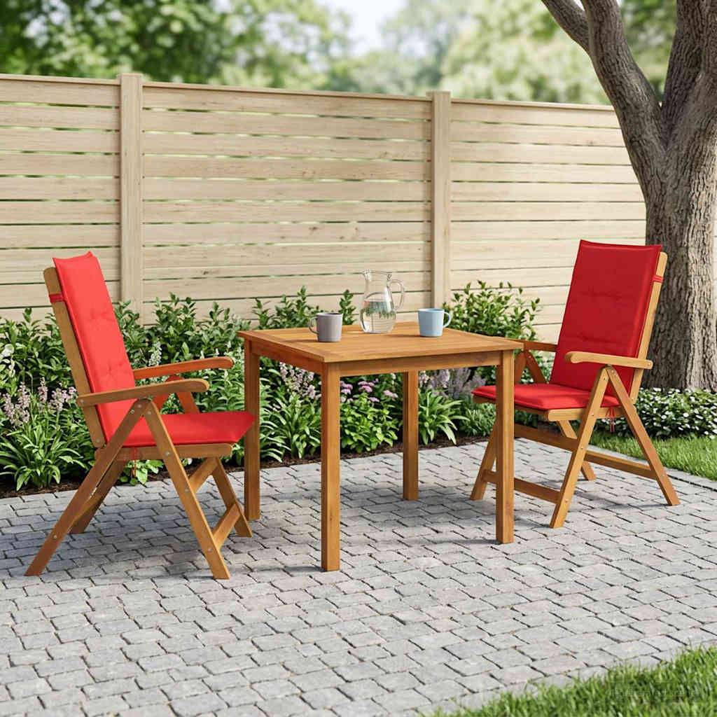 Außenbereich einer Terrasse mit zwei roten Holzstühlen und einem kleinen Holztisch auf Steinpflaster neben einem Zaun und einem Baum.