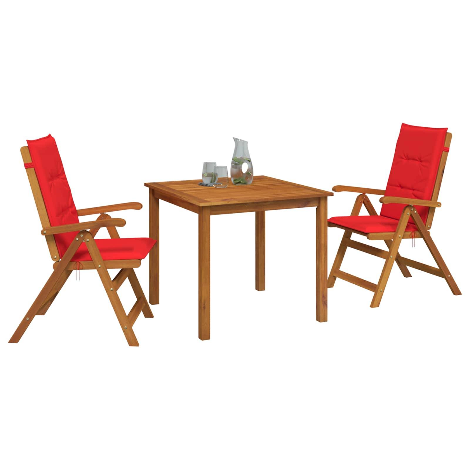 Zwei rote gepolsterte Holzstühle stehen sich an einem kleinen Holztisch gegenüber, auf dem Gläser und eine Flasche auf weißem Hintergrund stehen.