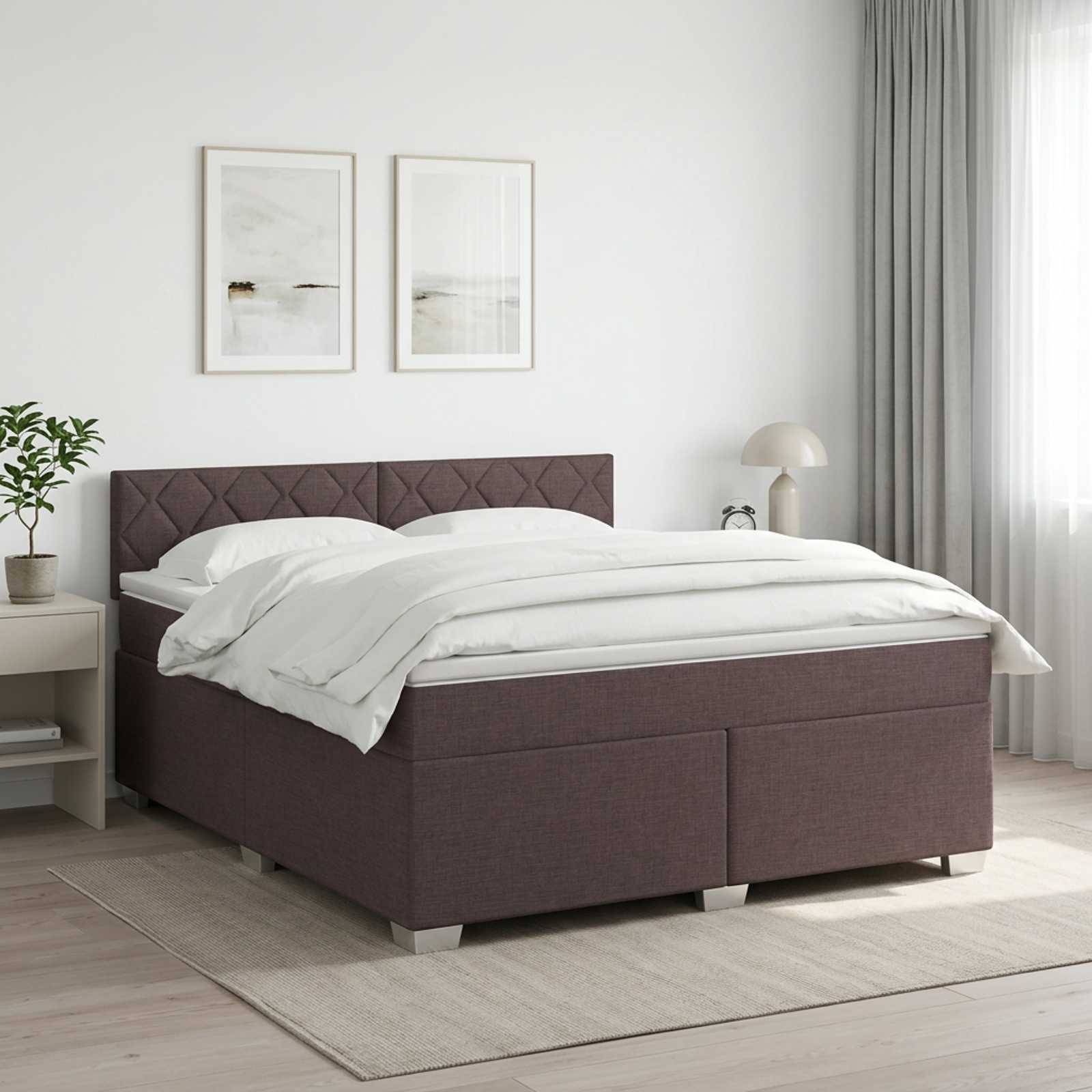 Ein ordentlich gemachtes Bett mit weißer Bettwäsche und einer dunkel gepolsterten Basis steht in einem hellen, minimalistischen Schlafzimmer mit gerahmter Wandkunst und einer Nachttischlampe.
