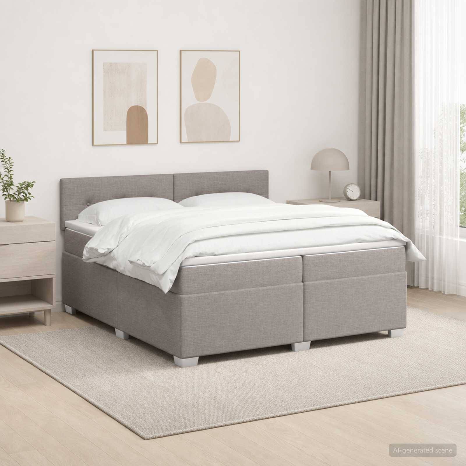 Ein grau gepolstertes Bett mit weißer Bettwäsche in einem hellen minimalistischen Schlafzimmer mit gerahmten Wandbildern, einem Nachttisch, einer Lampe und durchsichtigen Vorhängen.