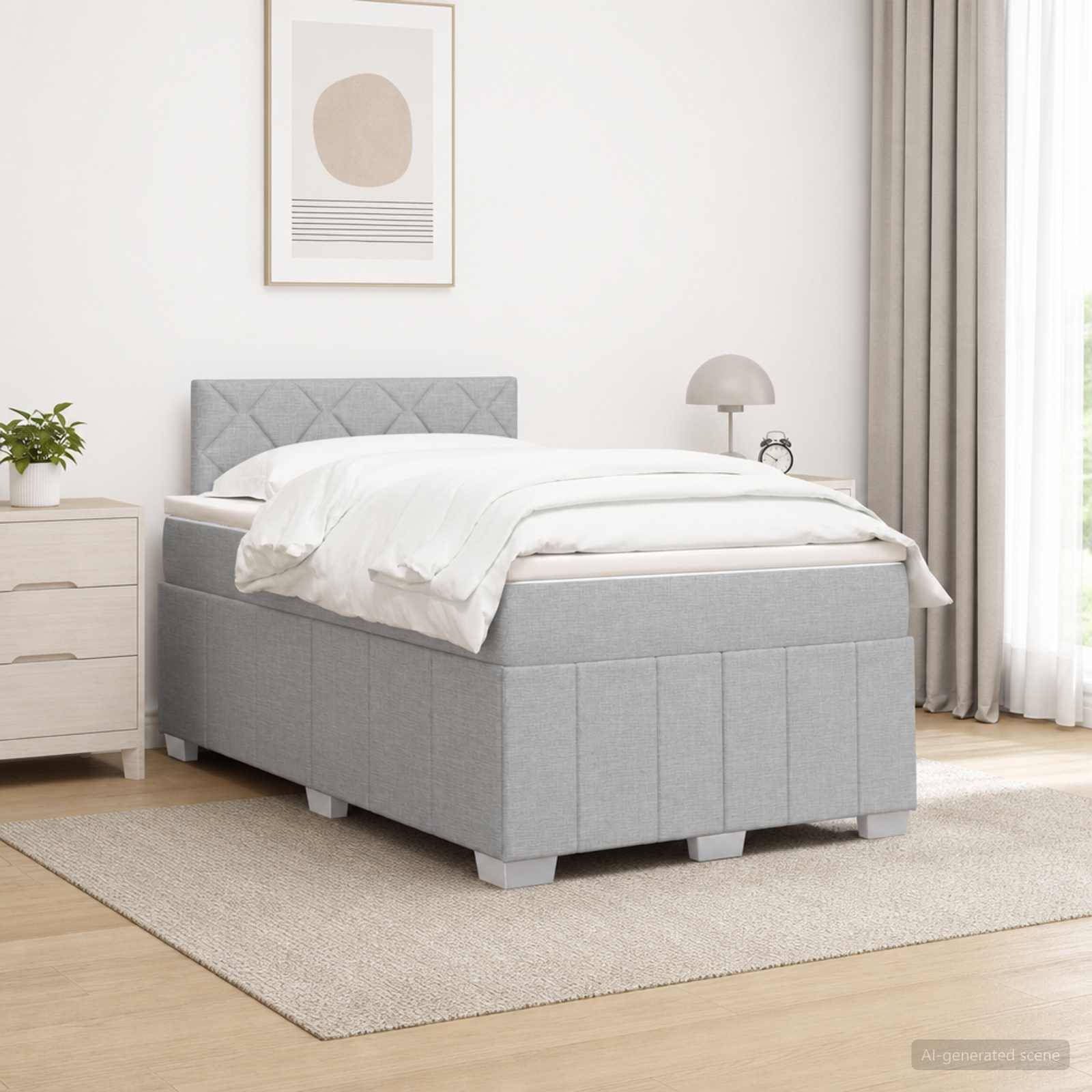 Ein grau gepolstertes Bett mit gestepptem Kopfteil und ottomanischem Sockel in einem hellen, minimalistischen Schlafzimmer mit Nachttisch, Lampe und gerahmter Wandkunst.