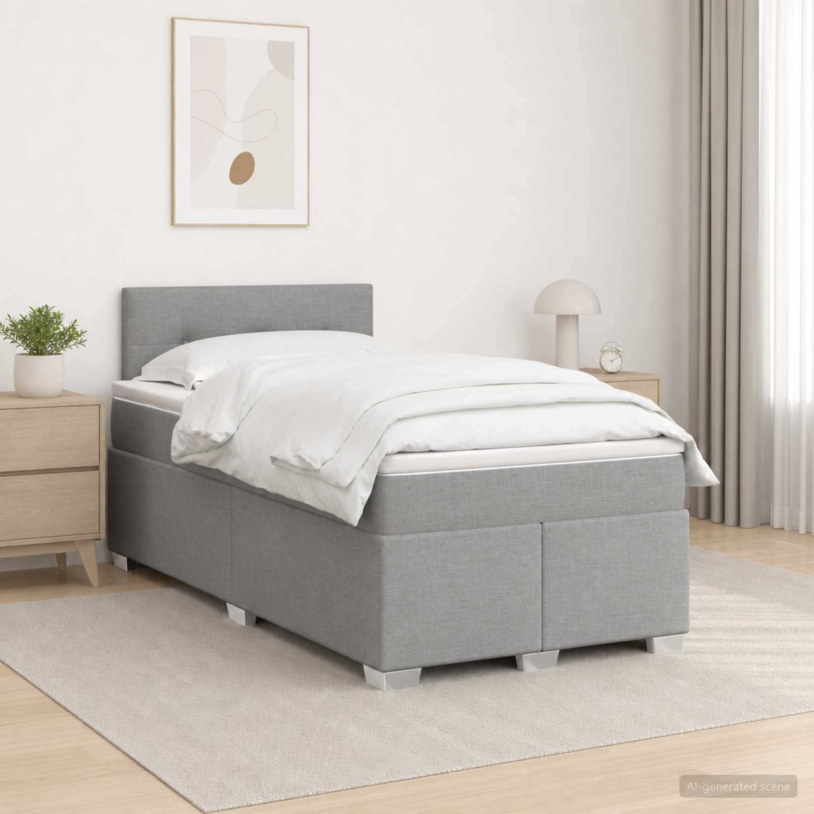 Modernes graugepolstertes Einzelbett mit weißer Bettwäsche in einem hellen, minimalistischen Schlafzimmer, flankiert von Nachttischen und einer Lampe.