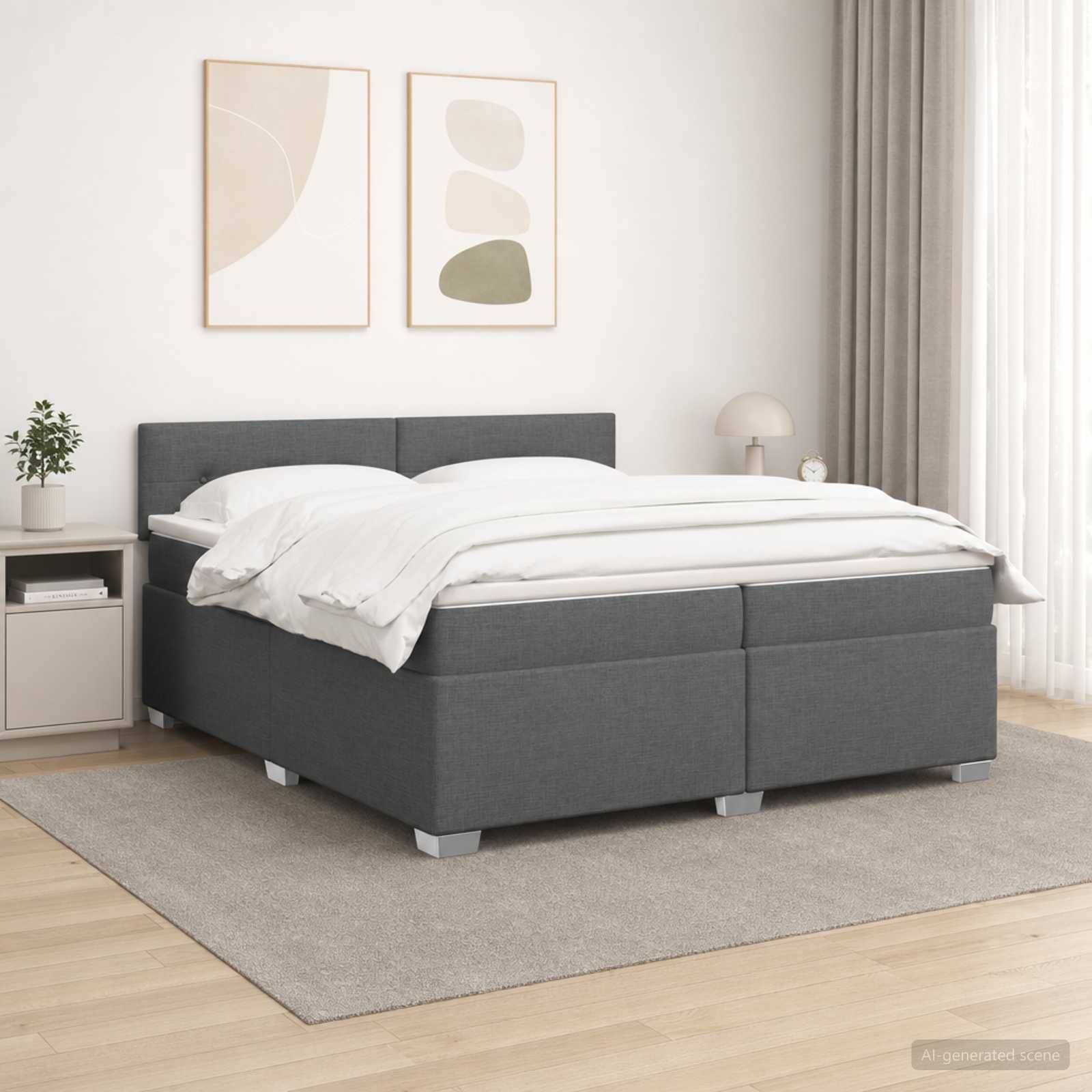 Grau gepolstertes Bett mit weißer Bettwäsche in einem minimalistischen Schlafzimmer mit gerahmten Wandbildern, Nachttisch, Lampe und Teppich.