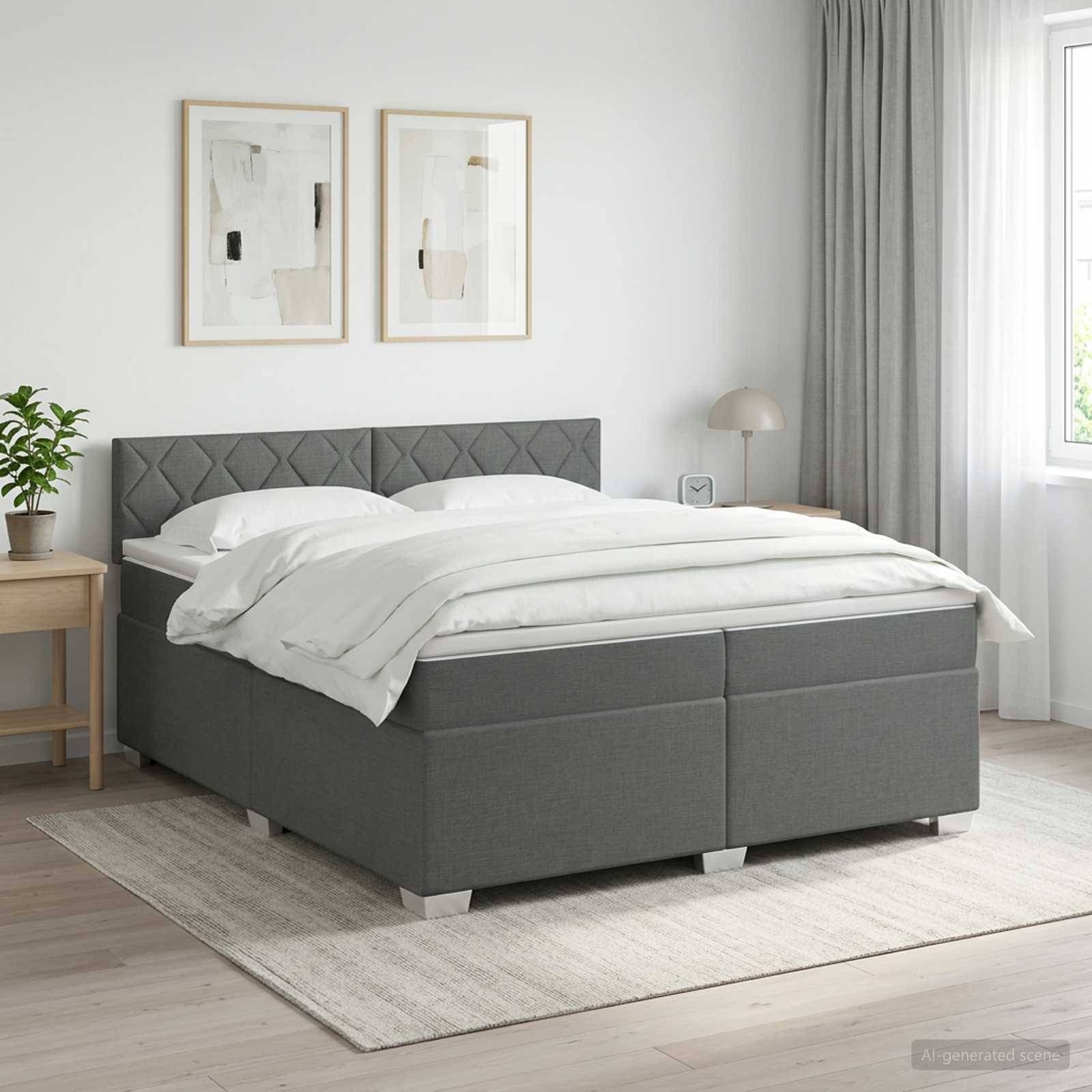 Ein grau gepolstertes Bett mit weißer Bettwäsche in einem hellen minimalistischen Schlafzimmer mit Wandkunst in Rahmen, einem Nachttisch, einer Lampe, einer Pflanze und einem großen Fenster.