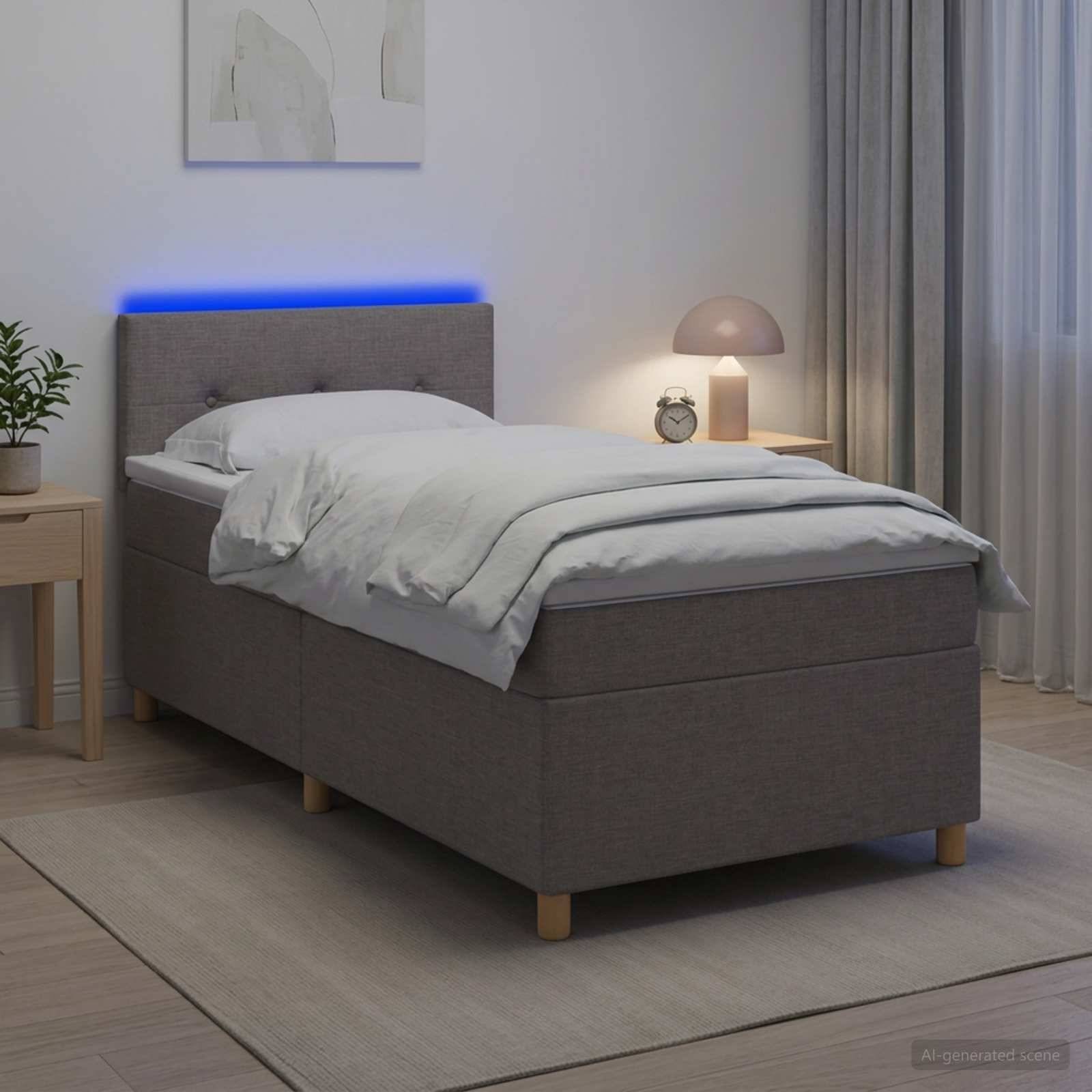 Modernes graues Einzelbett mit weißer Bettwäsche, blau beleuchtetes Kopfende, Nachttisch und Lampe in einem sanft beleuchteten Schlafzimmer.