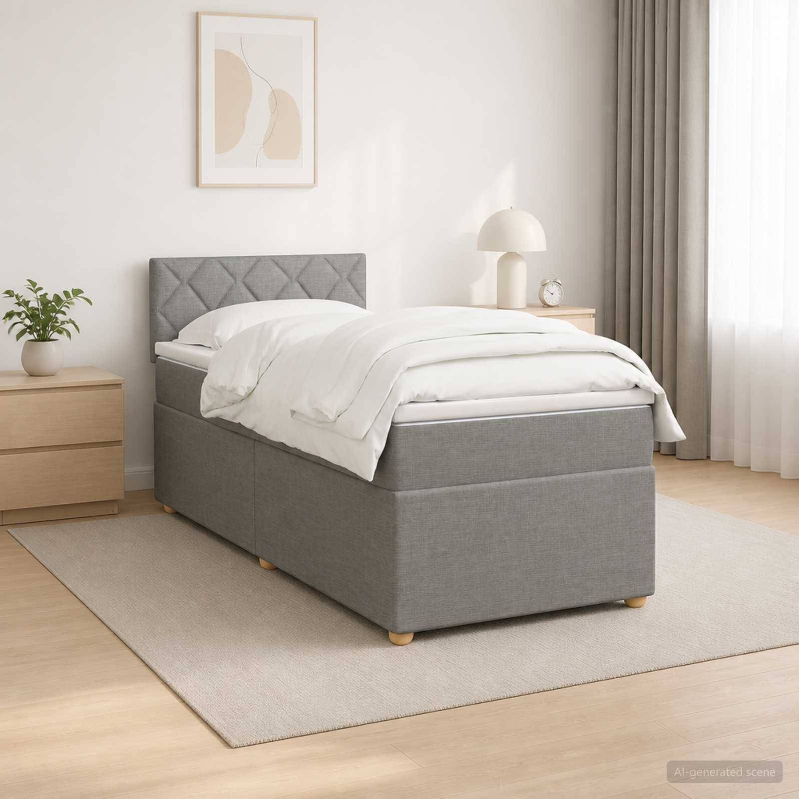 Ein modernes, grau gepolstertes Einzelbett mit weißer Bettwäsche in einem hellen, minimalistischen Schlafzimmer neben einem Nachttisch, einer Lampe, einer Pflanze und einem gerahmten Wandbild.
