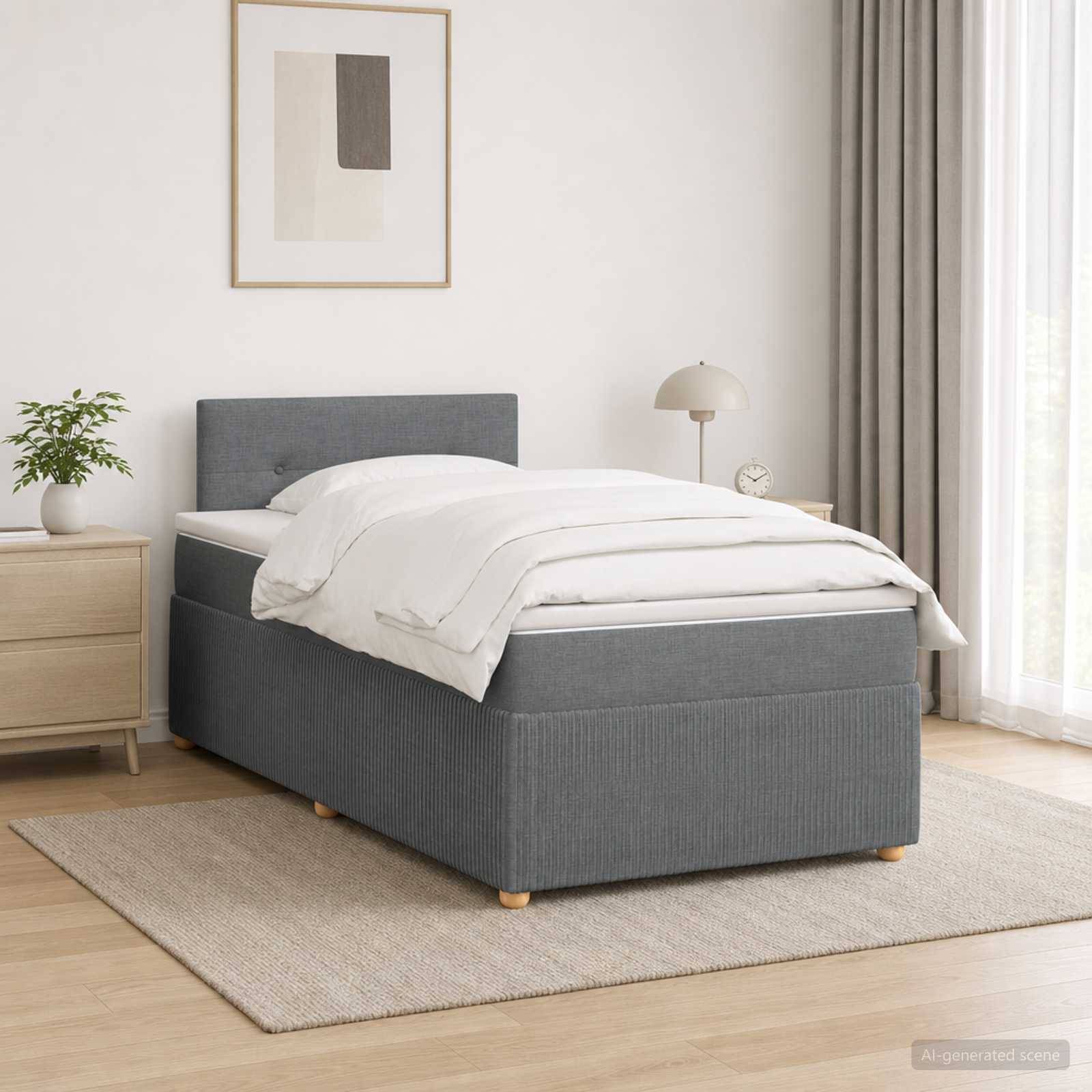 Grau gepolstertes Bett mit weißer Bettwäsche in einem hellen, minimalistischen Schlafzimmer neben einem Nachttisch, einer Lampe und gerahmter Wandkunst.