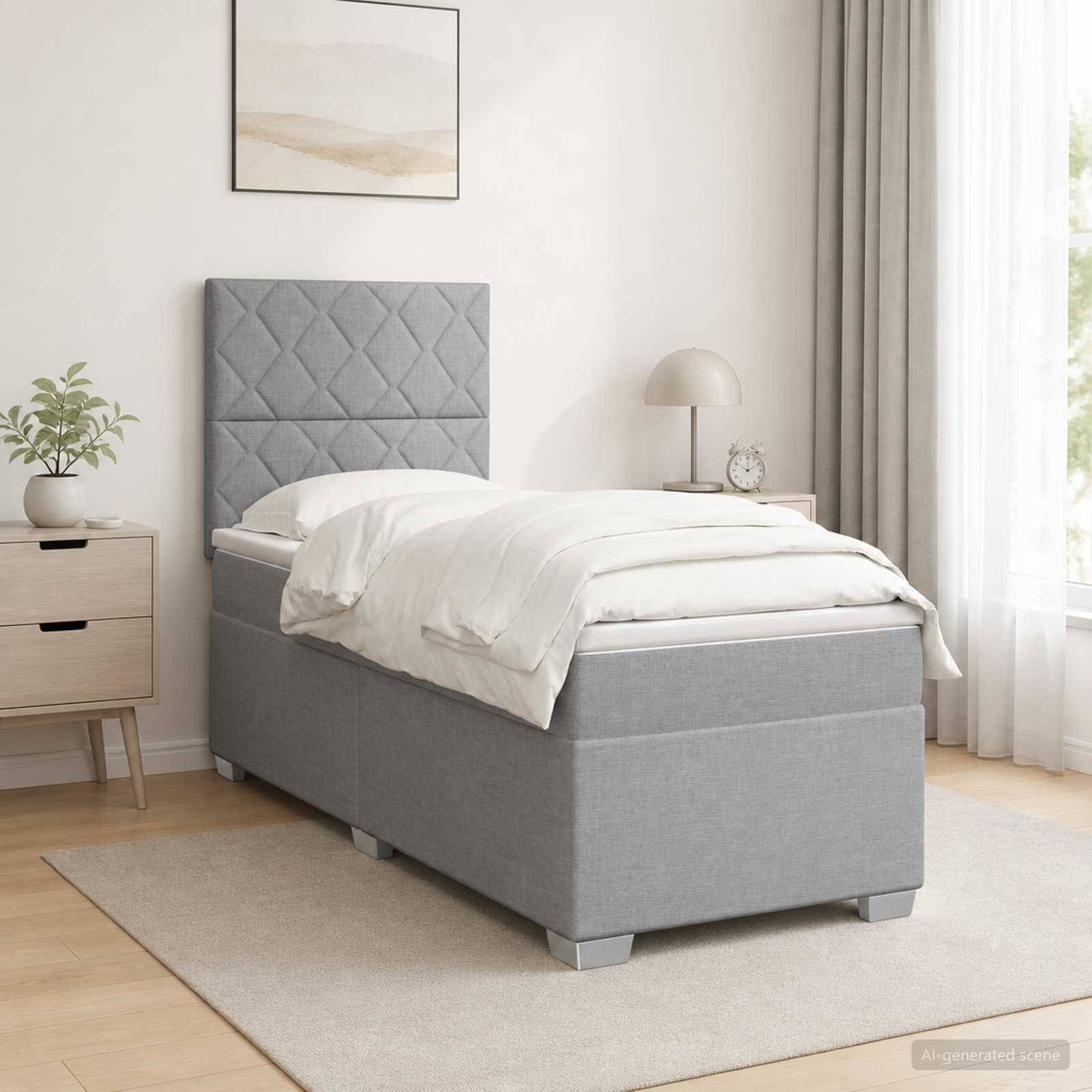 Ein grau gepolstertes Einzelbett mit rautengestepptem Kopfteil in einem hellen, minimalistischen Schlafzimmer, ausgestattet mit weißer Bettwäsche, Nachttisch, Lampe, Pflanze und Wandkunst.