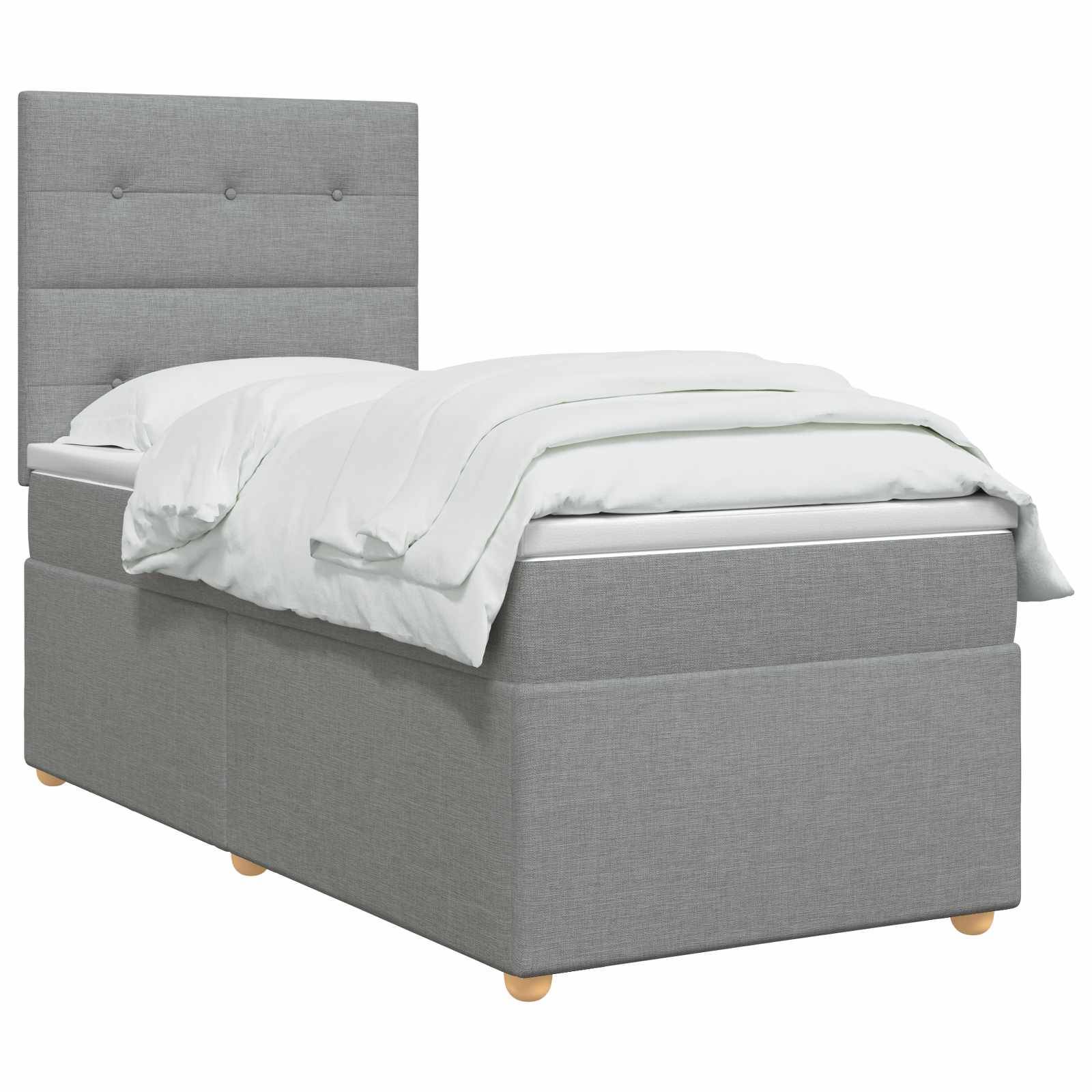 Grau gepolstertes Einzelbett mit hohem, knopfgestepptem Kopfteil und weißer Bettwäsche auf einfachem weißem Hintergrund.